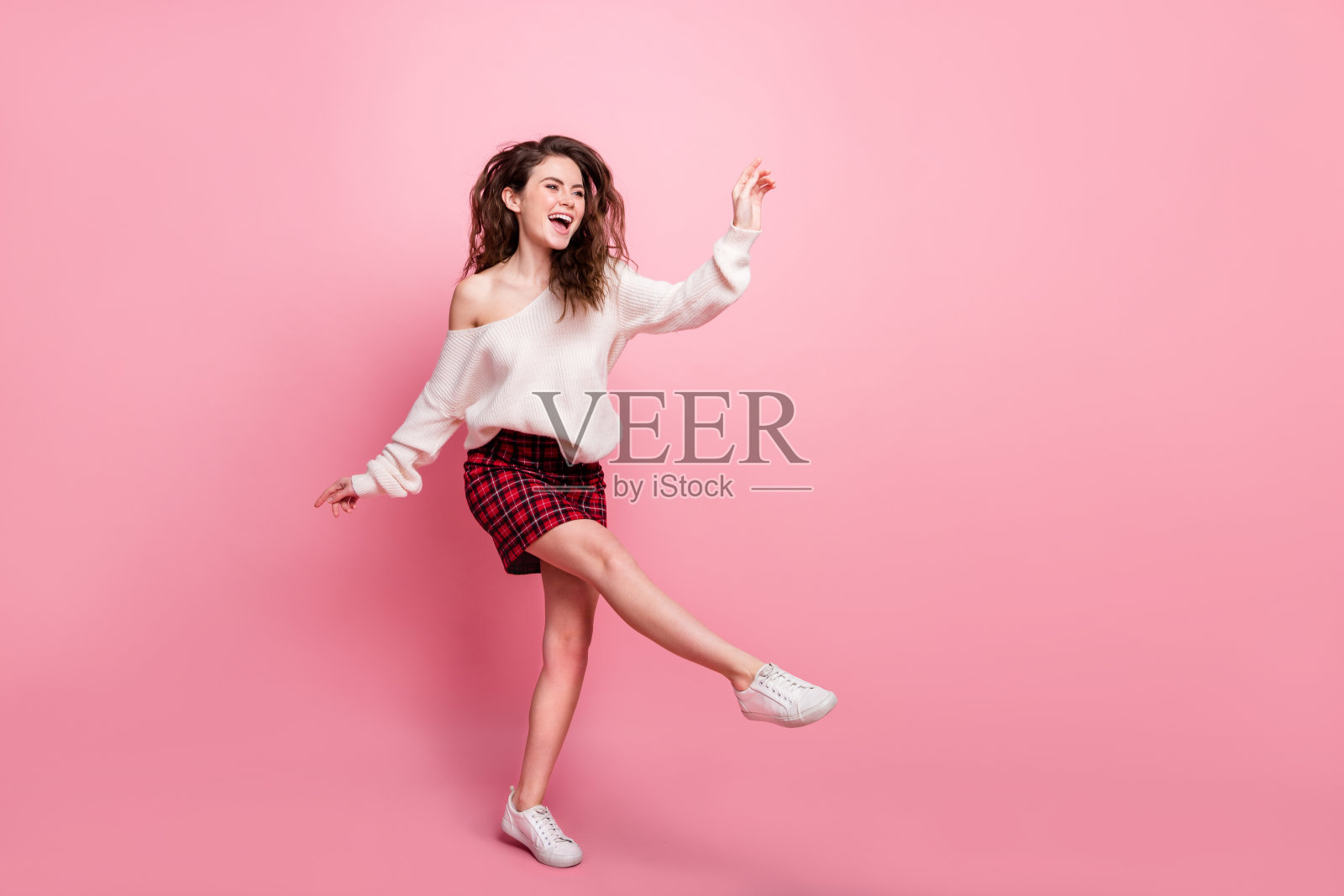 粉色背景下,年轻漂亮女孩全身侧面照,开心积极地笑着玩耍,独立于背景。照片摄影图片