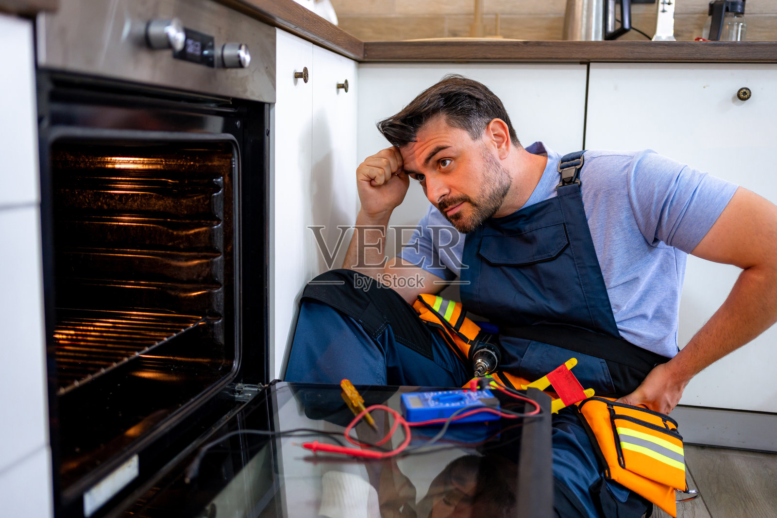 技术人员在现代厨房中检查烤箱是否存在问题照片摄影图片