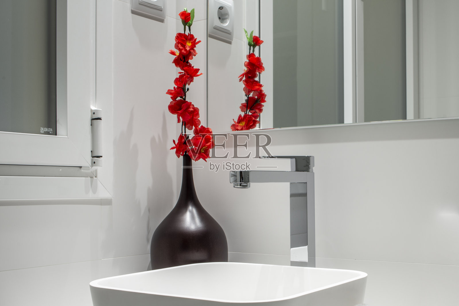 带红色花朵罐子的小型卫生间的装饰细节,配有白色陶瓷水槽照片摄影图片