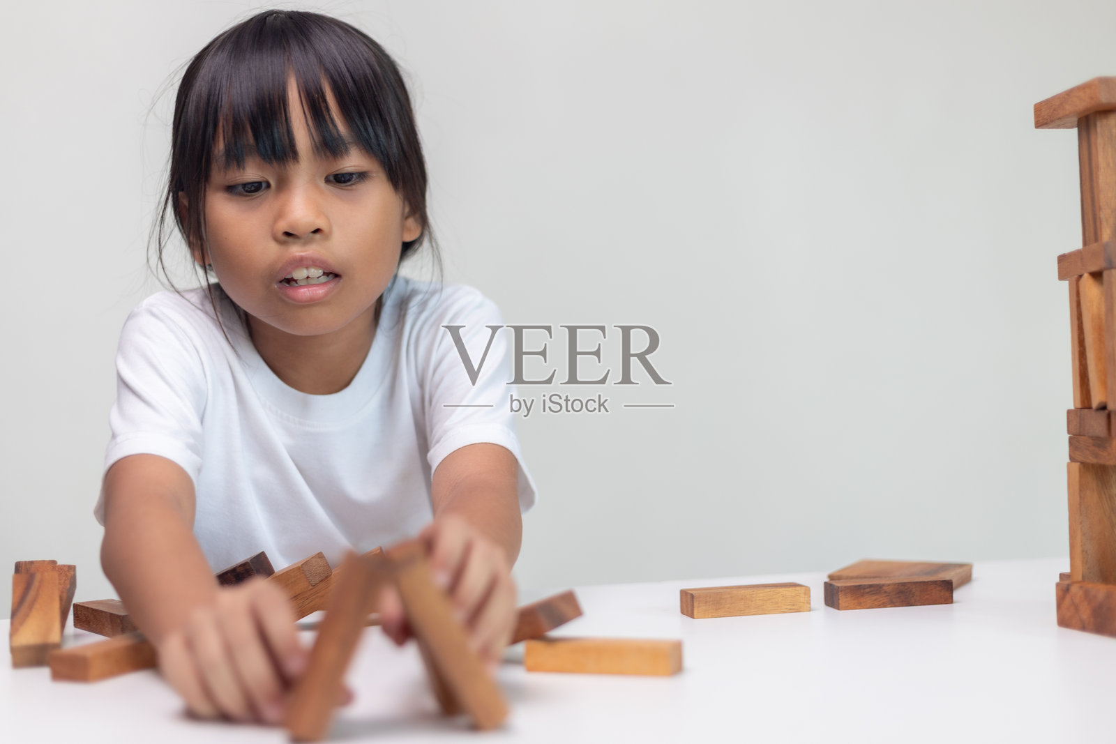 亚洲儿童在家中玩耍木制积木,进行学习和实验,寓意STEM教育、好奇心、解决问题、创造力和儿童发展照片摄影图片