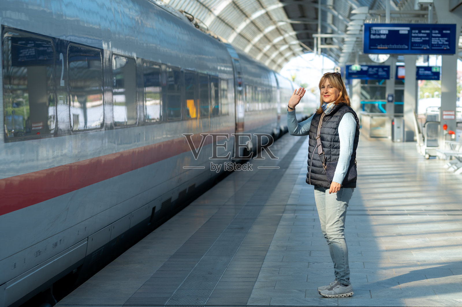 一辆火车驶来,一位女士站在空旷的站台上,这是火车的正面视角。照片摄影图片