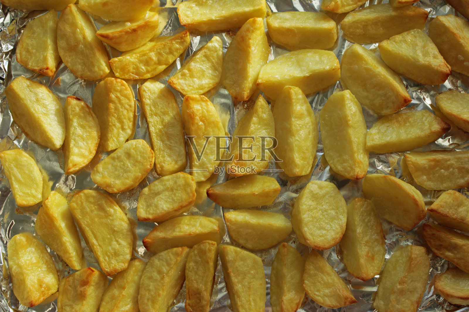 烘烤的土豆角放在锡纸上,俯视角度。照片摄影图片