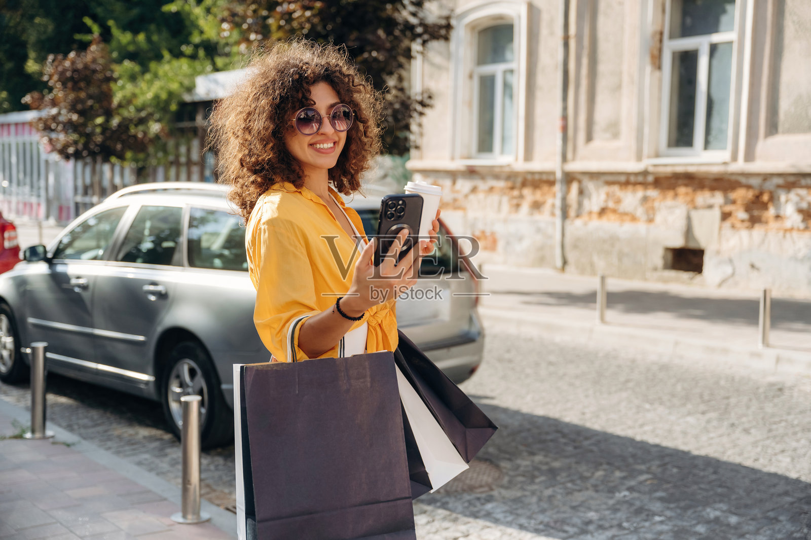 快乐的女人提着购物袋在城里闲逛。照片摄影图片