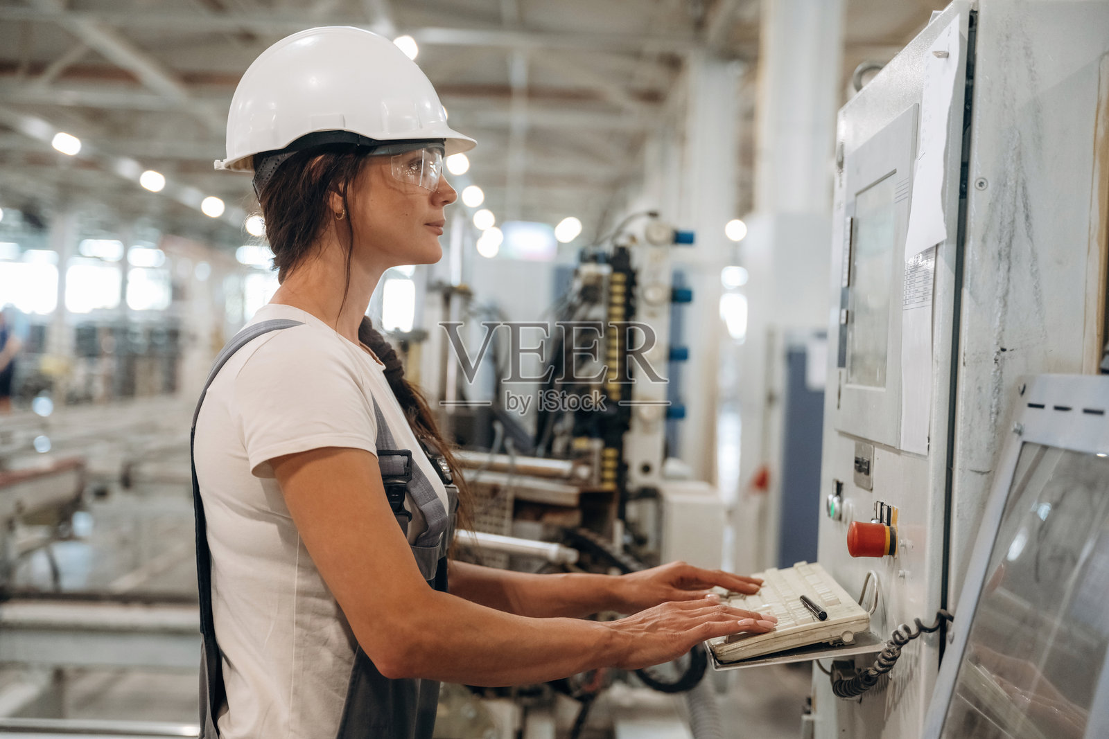 女机械操作员的侧面视图,她在工厂的窗户里工作照片摄影图片