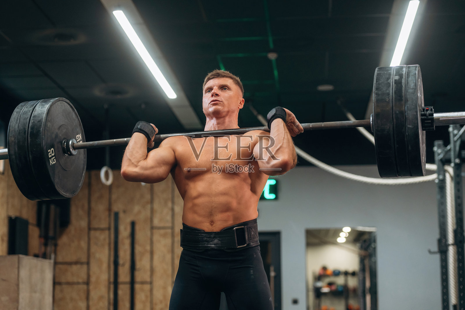 专注右侧技巧。一名健壮的男子在健身房进行杠铃举重训练。照片摄影图片