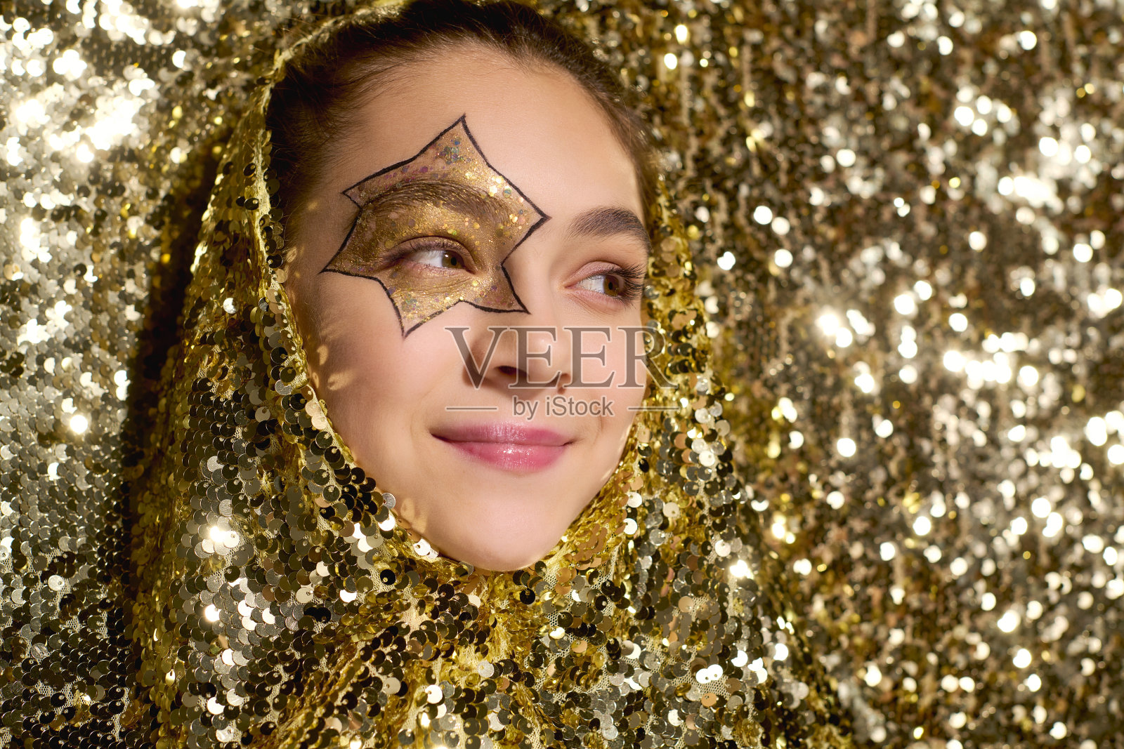 可爱的女孩脸上画着星星,在金色亮片中闪耀照片摄影图片