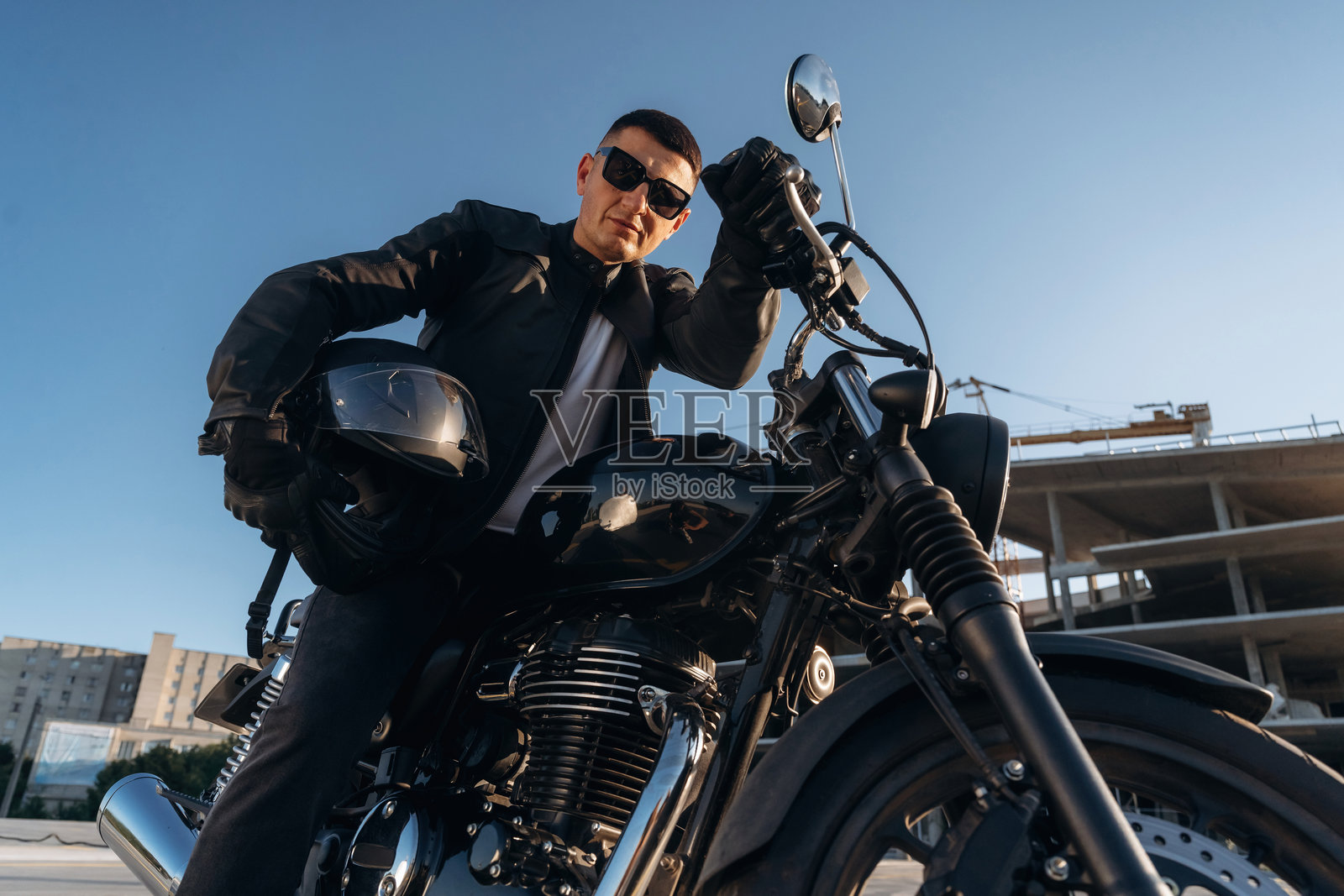 自豪的摩托车主。男子在户外和他心爱的摩托车在一起。照片摄影图片