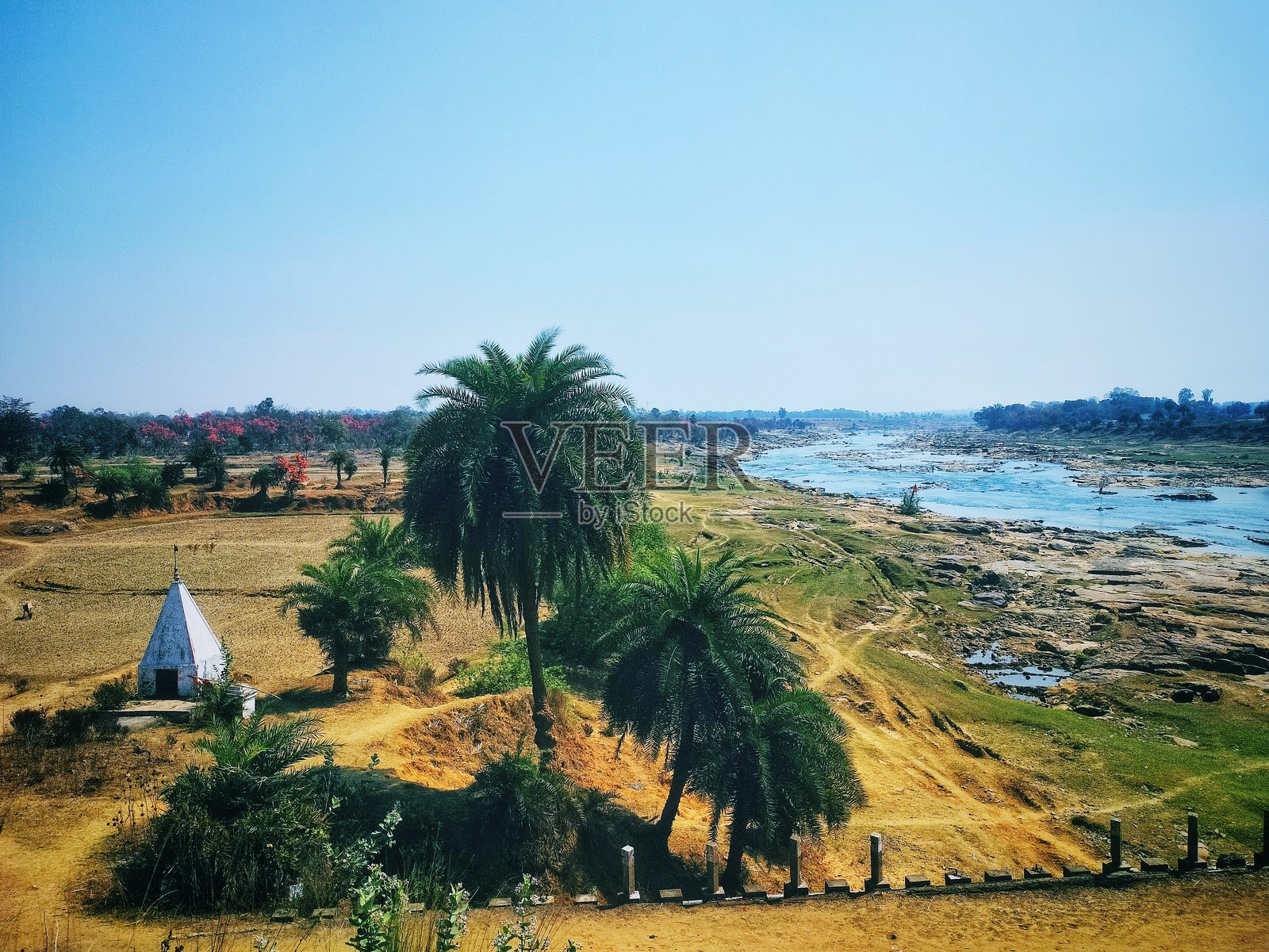 干旱的河岸风光,点缀着棕榈树和一座白色神龛照片摄影图片