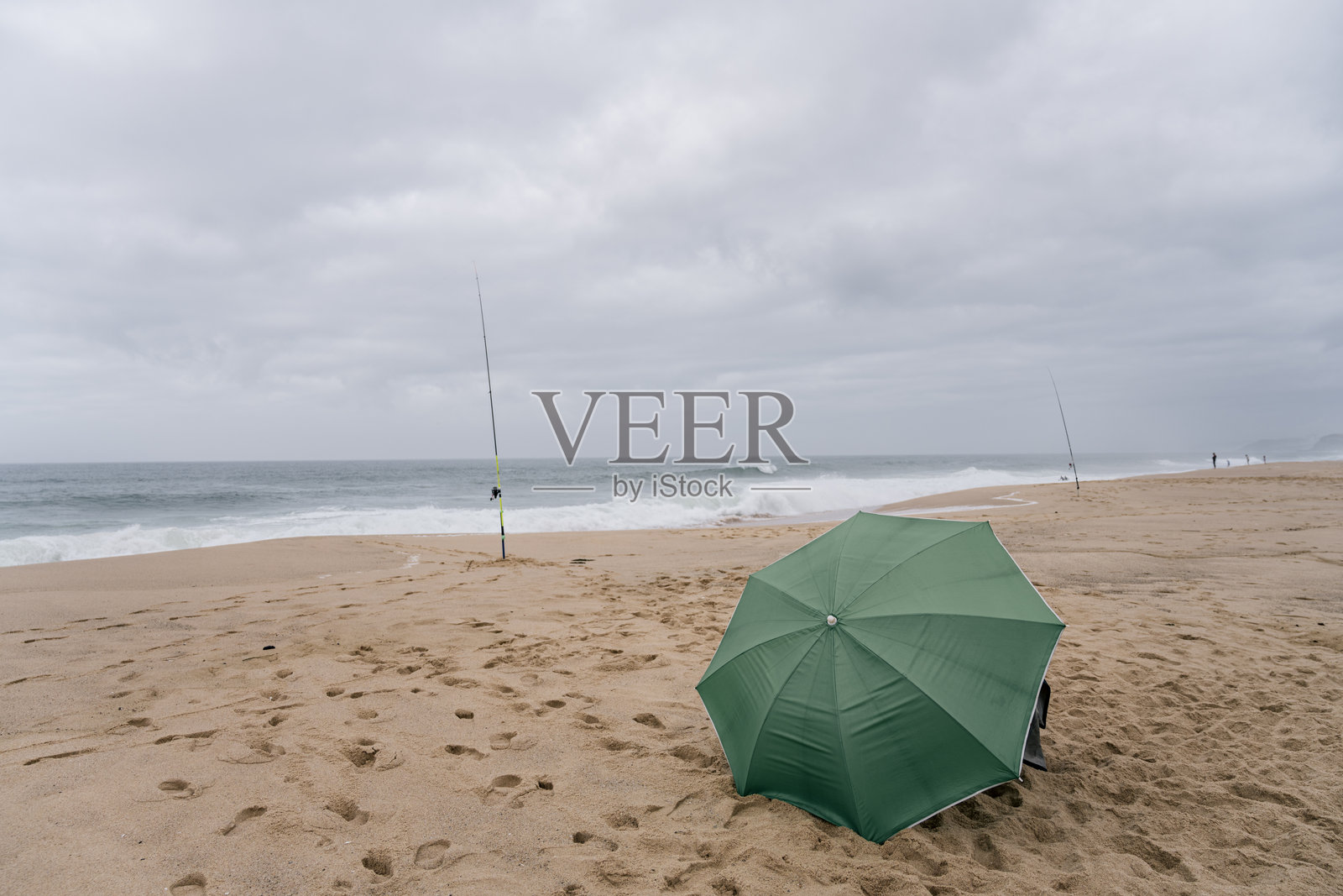 葡萄牙科英布拉圣克鲁斯沙滩上的绿色雨伞和钓鱼竿照片摄影图片