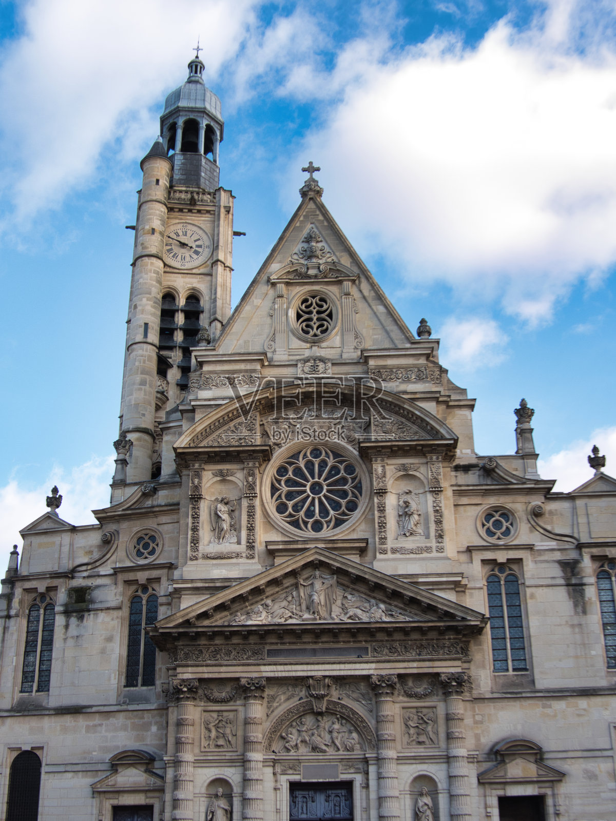 圣艾蒂安·迪蒙教堂钟楼——从低角度戏剧性地拍摄,展示了历史悠久的圣艾蒂安·迪蒙教堂高度精细的正面和独特的钟楼,背景是充满活力的多云蓝天。照片摄影图片