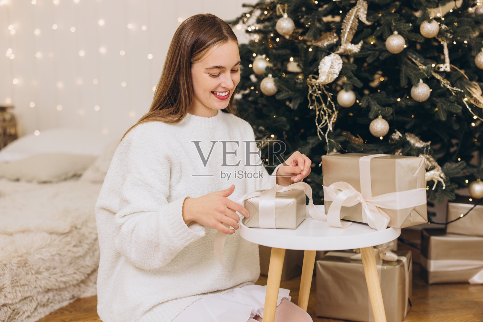 女人在装饰的圣诞树旁包装圣诞礼物照片摄影图片