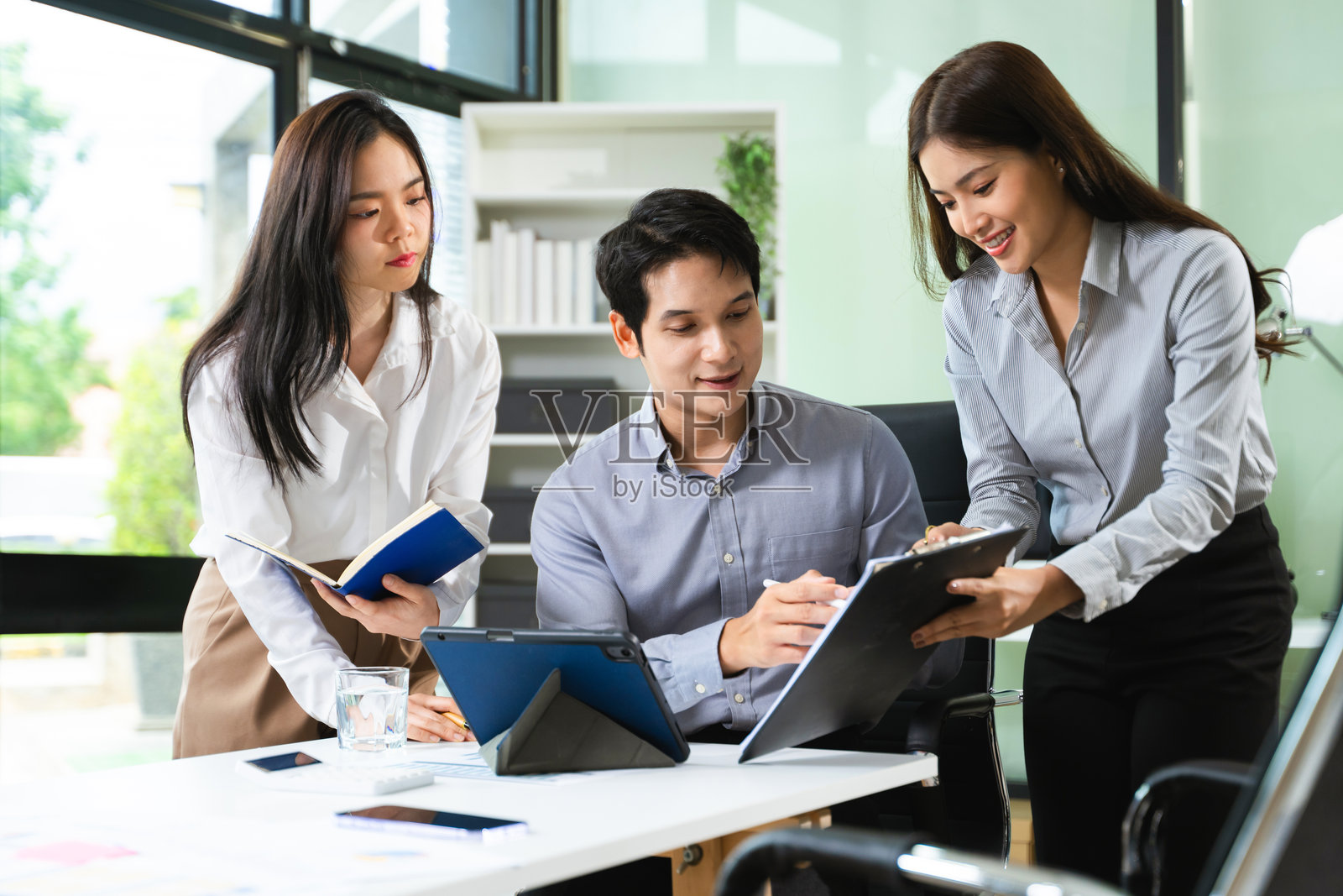 年轻的商务专业人士在现代办公室里协同工作,使用平板电脑和笔记本电脑。初创公司,团队合作照片摄影图片