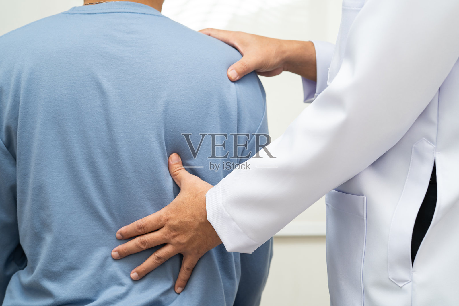 物理治疗,亚洲治疗师医生在医院治疗年轻男子的疼痛。照片摄影图片