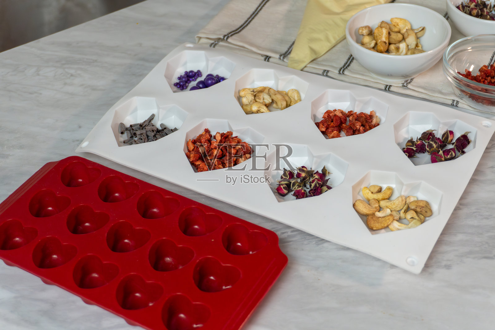 厨房台面上的心形硅胶模具,配有坚果和干果配料照片摄影图片