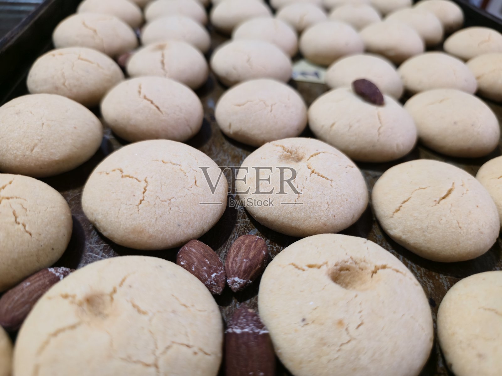 烤箱托盘上摆放着新鲜出炉的、撒有杏仁的印度酥饼照片摄影图片