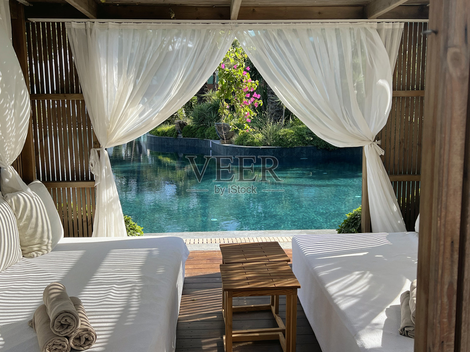 带泳池景致的木质躺椅和白色窗帘照片摄影图片