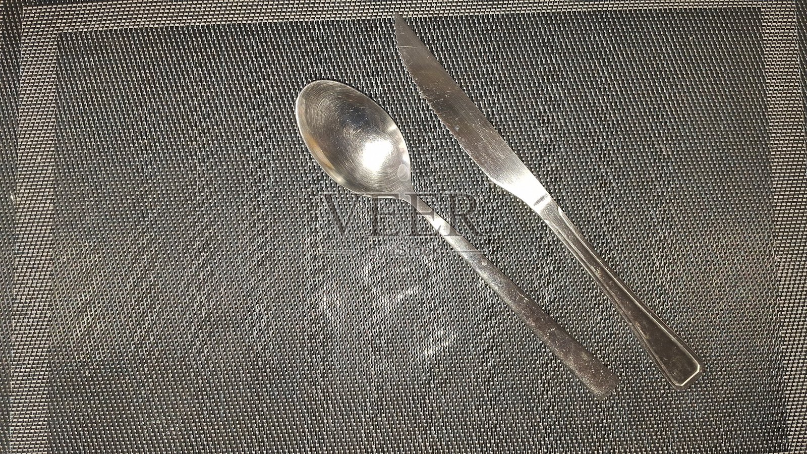 黑色尼龙毛巾上的面包刀和金属勺照片摄影图片