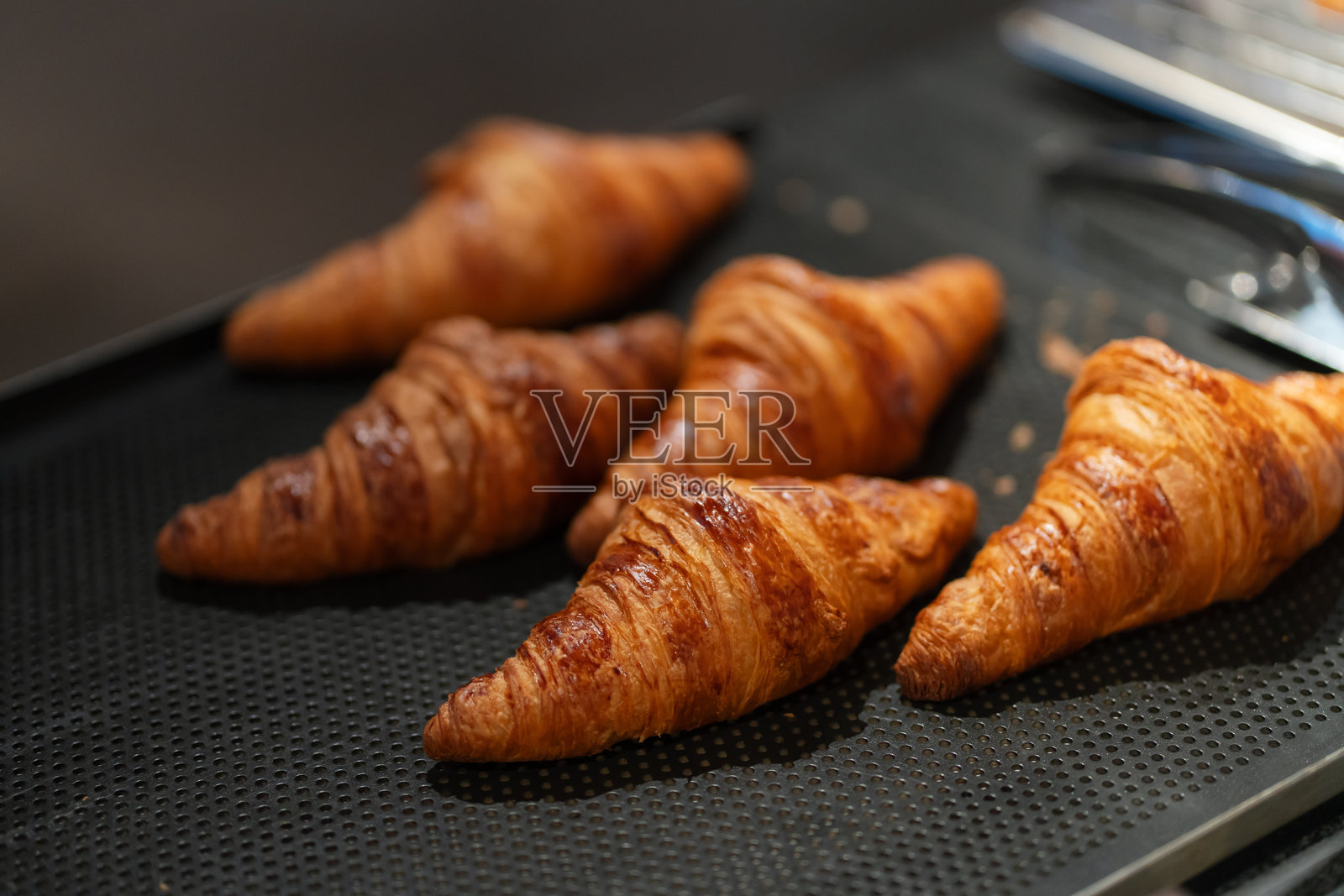 刚出炉的金黄色可颂面包在托盘上准备好,供自助早餐享用。照片摄影图片