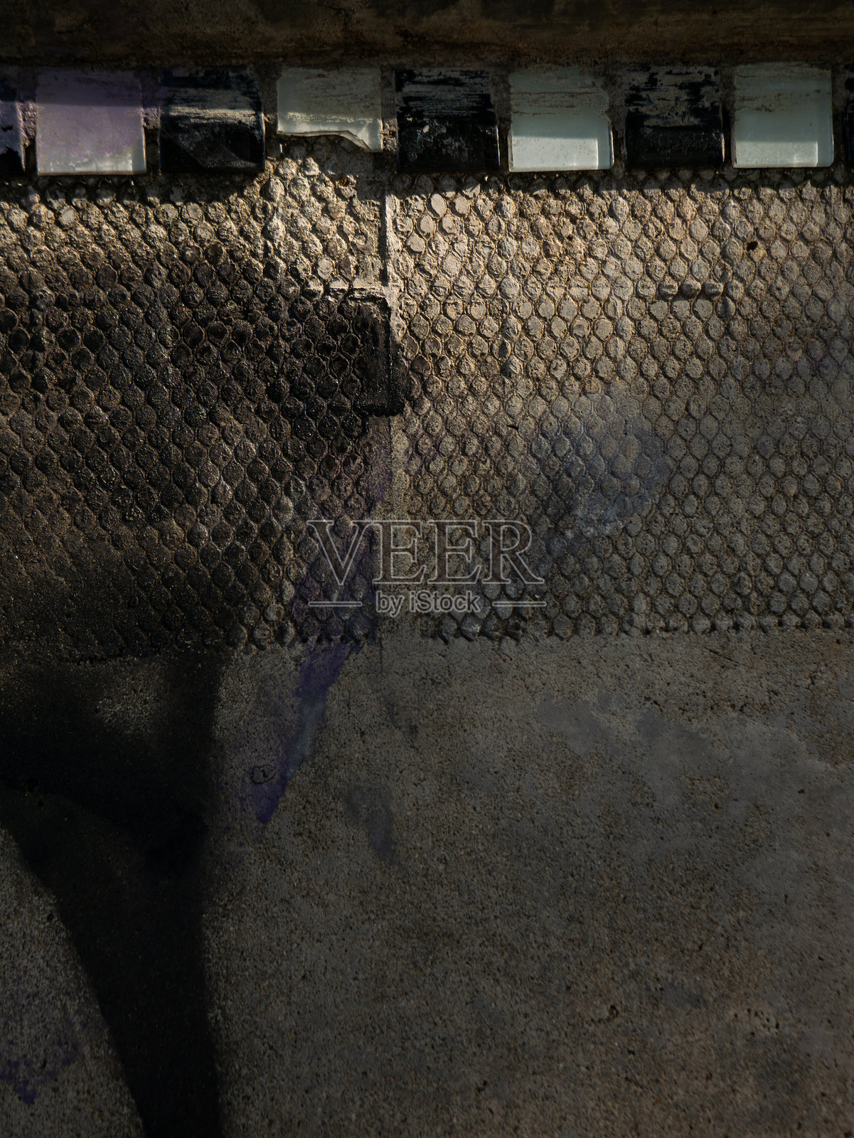 破损肮脏的玻璃砖窗户瓷砖从风化的墙壁上脱落,在混凝土地面上投下戏剧性的阴影照片摄影图片