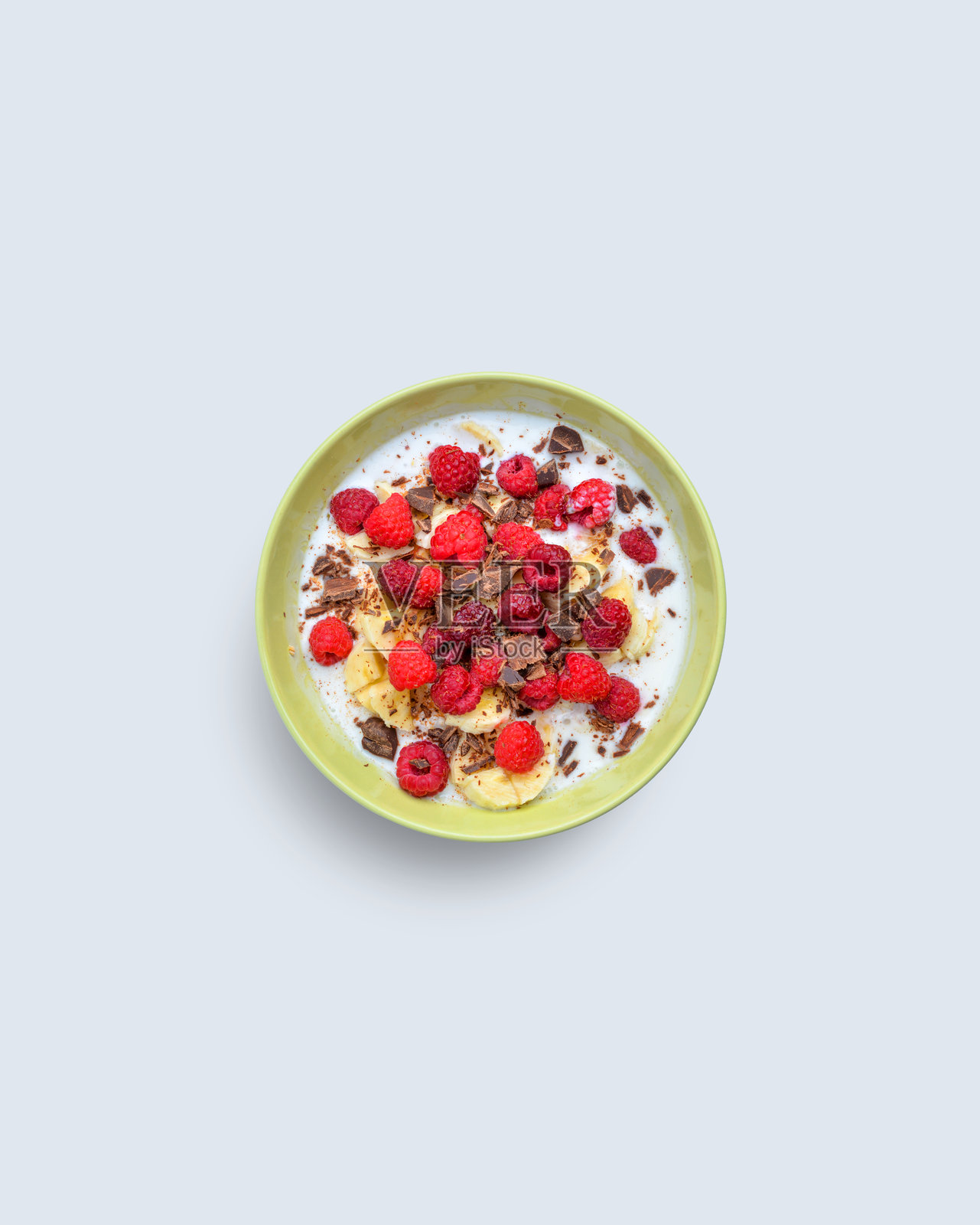 色彩缤纷的早餐碗,内有香蕉、覆盆子、巧克力和酸奶,置于浅色背景上,象征健康营养与早晨活力照片摄影图片