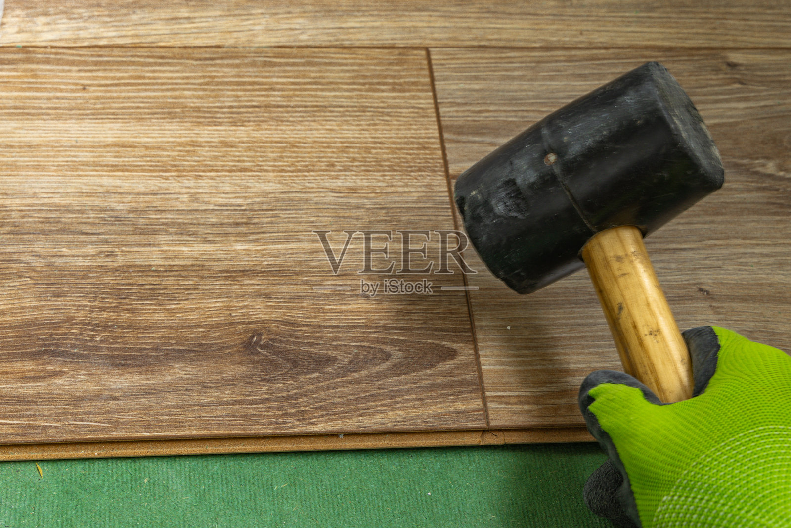使用橡胶锤安装木地板面板的家居装修工作照片摄影图片