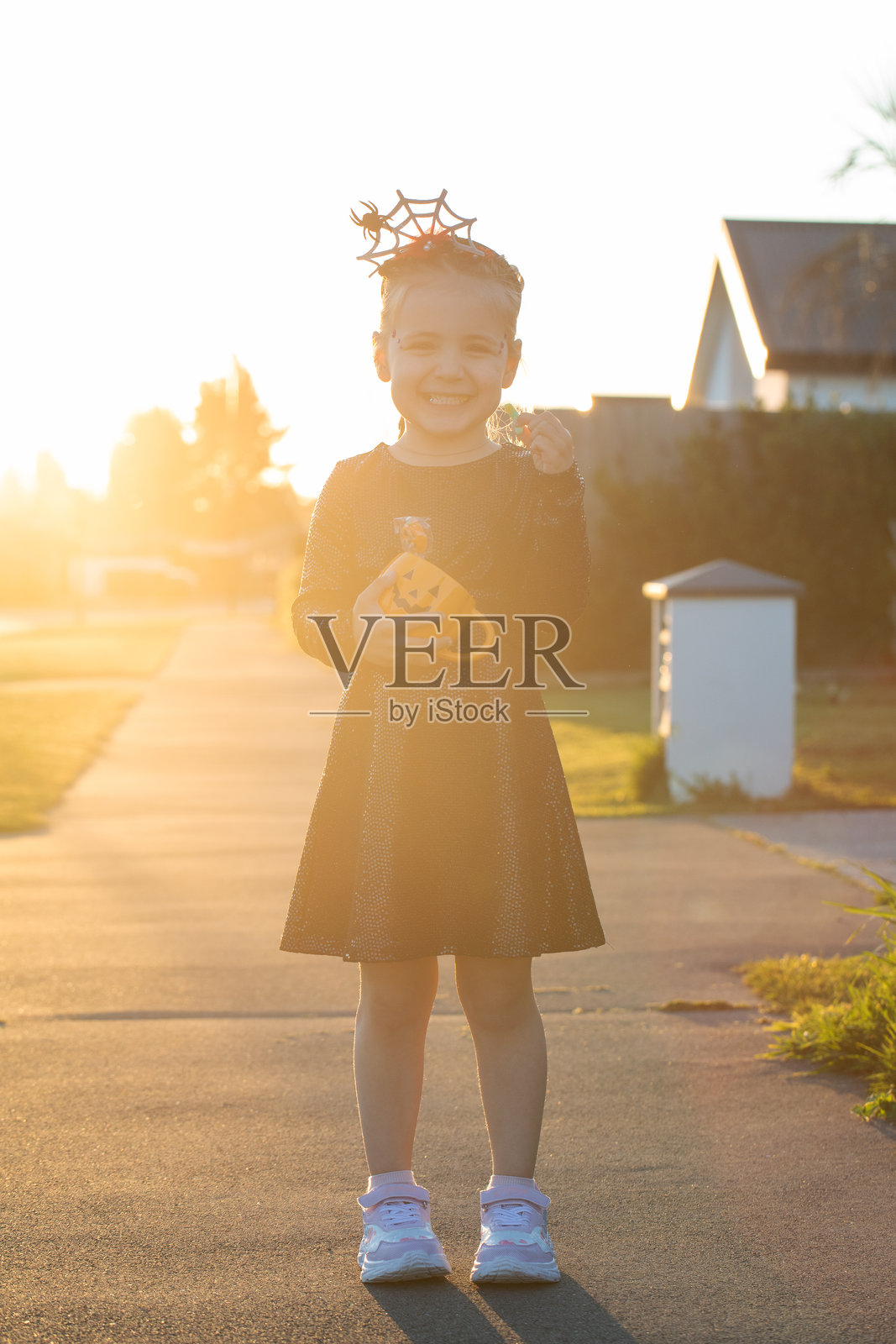 可爱的女孩穿着万圣节服装,在户外提着装满糖果的南瓜篮子照片摄影图片