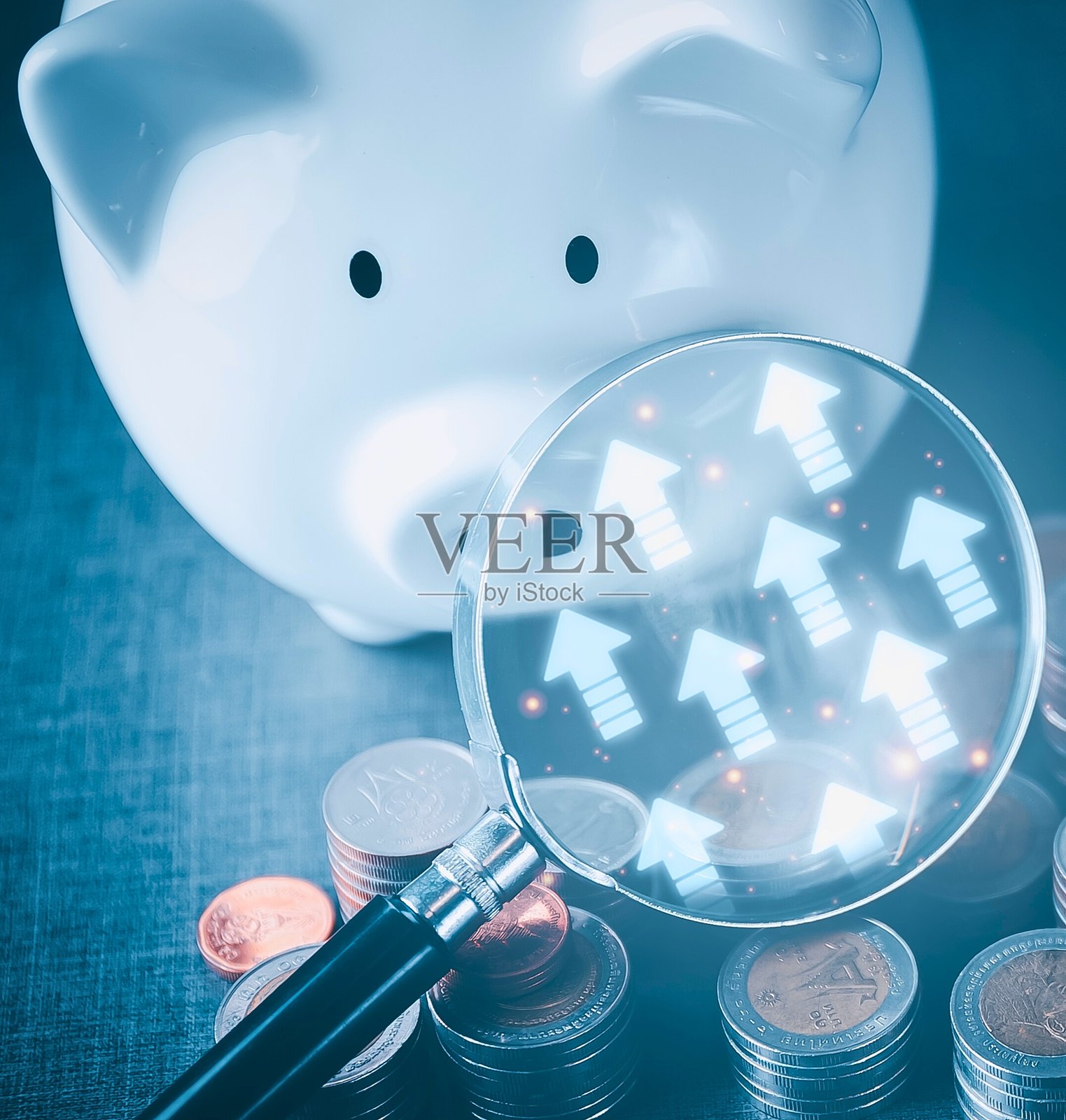 放大镜下的存钱罐显示着向上的箭头照片摄影图片