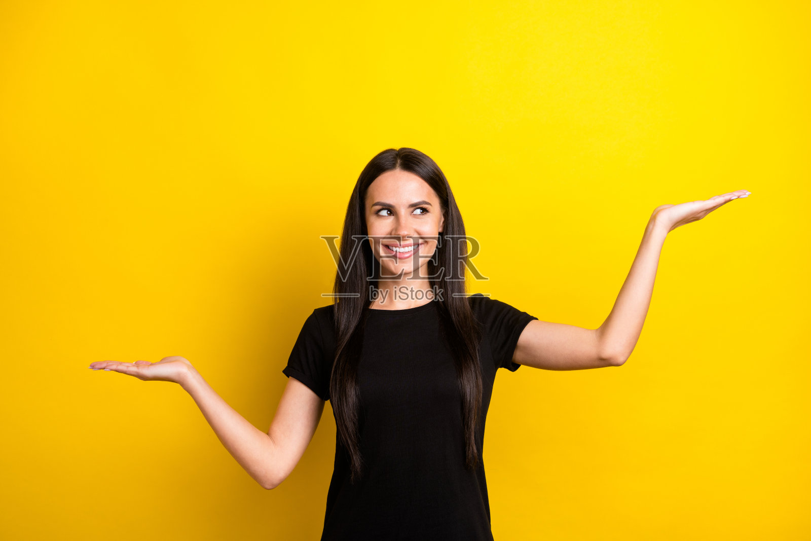 一个面带灿烂笑容、伸出双手手掌、展示空无一物的衡量天平,肖像照,与黄色背景隔离照片摄影图片