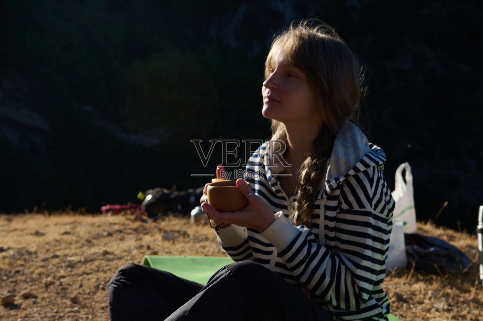 女子在宁静的黄昏露营之旅中,在户外享受着一杯茶的惬意时光。照片摄影图片