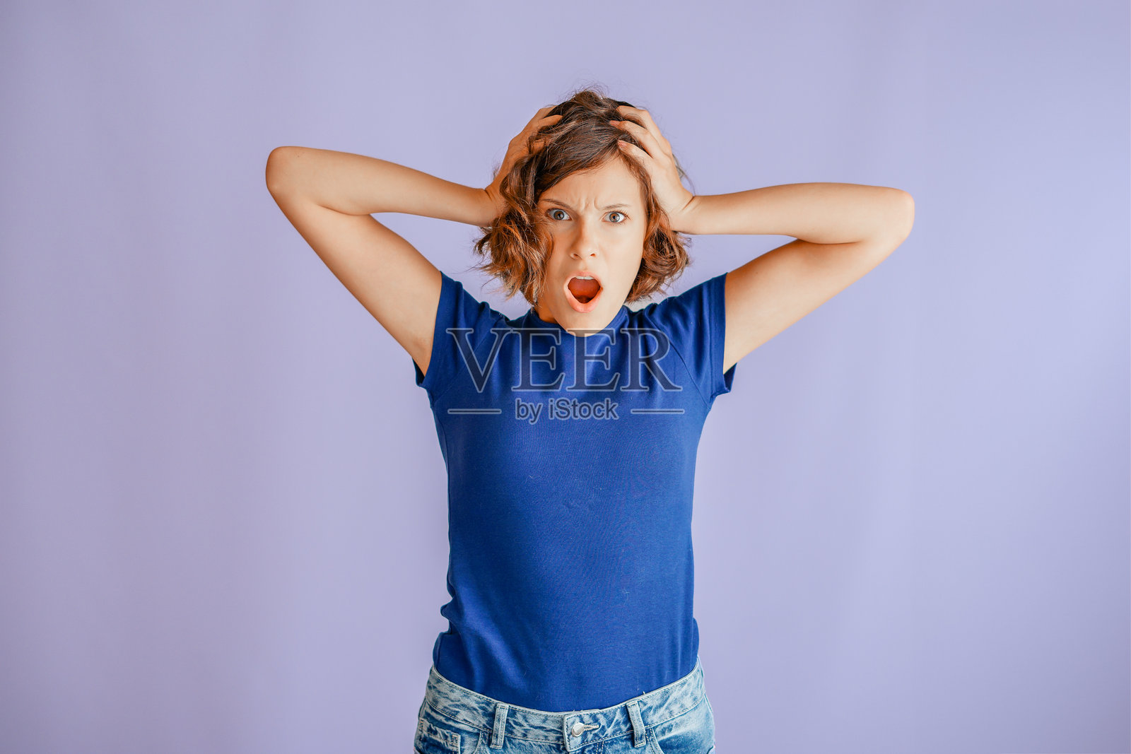 一个忧虑的年轻女孩,表情困惑,带着烦恼的表情和压抑的氛围,在充满焦虑情绪的鲜艳蓝色工作室背景下,传递着心理健康的概念。照片摄影图片