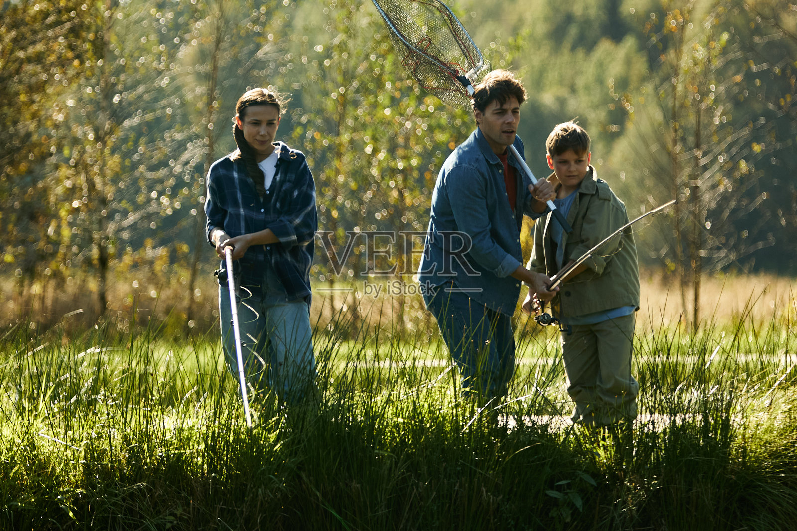 一位高加索女性与两个男孩在河岸边一起钓鱼照片摄影图片