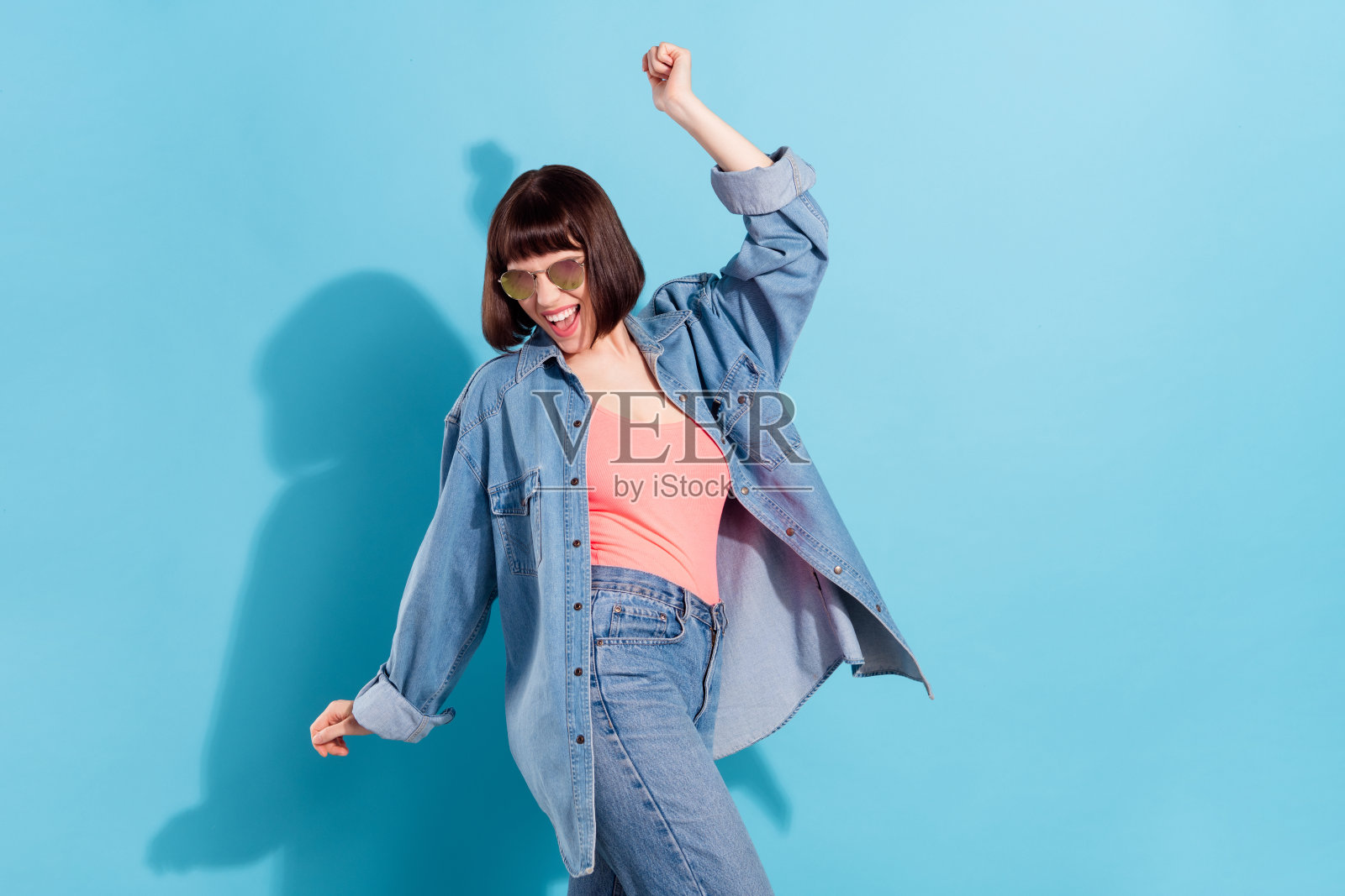 一位迷人的快乐女孩,在明亮的蓝色背景前跳舞,享受周末的乐趣,照片风格为肖像。照片摄影图片