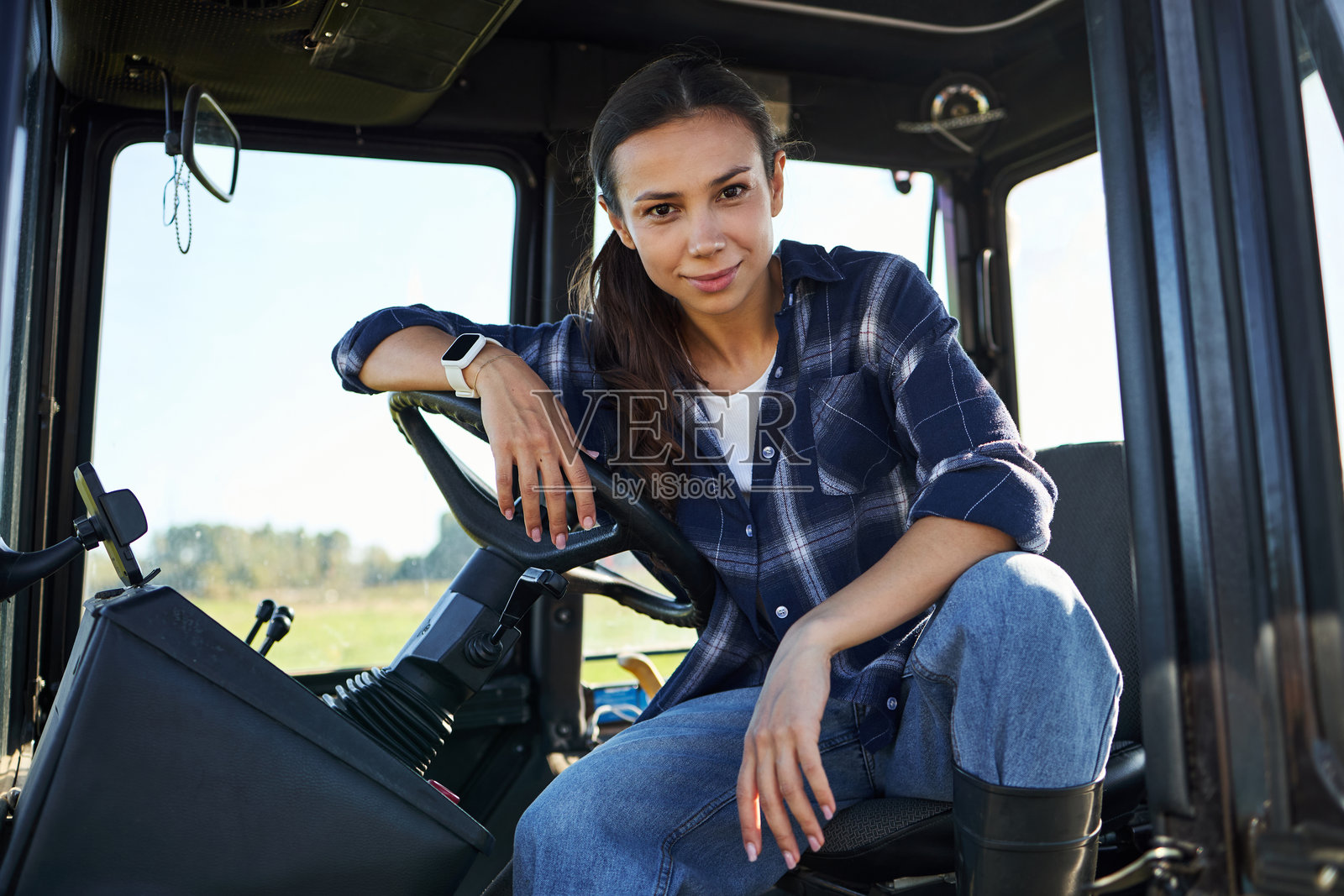 年轻成年白人女性坐在拖拉机驾驶室内的肖像,面带微笑照片摄影图片