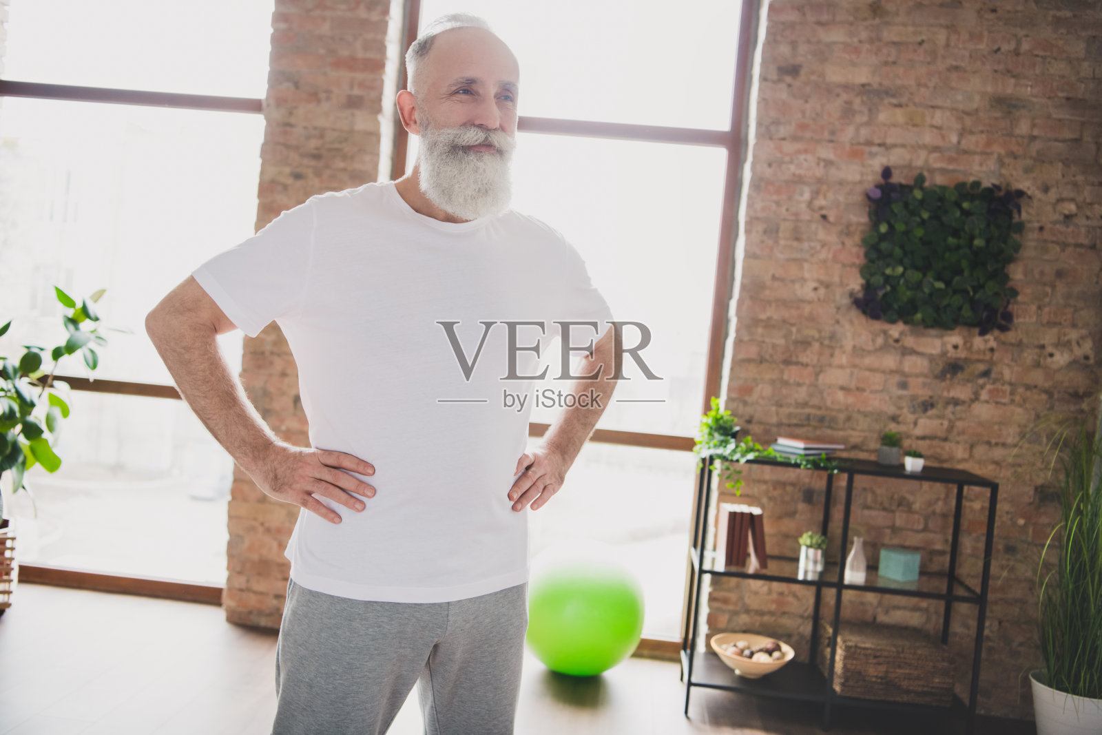 照片:一位快乐、微笑、心情愉悦、梦想家般英俊、成熟、留着胡须的男人在家中艰苦训练后放松照片摄影图片