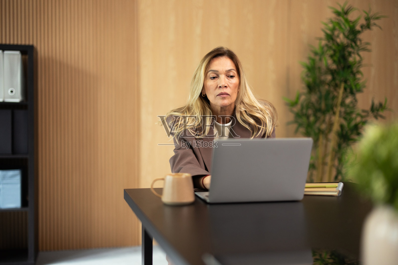 一位年长的女性在办公桌前使用电脑工作照片摄影图片