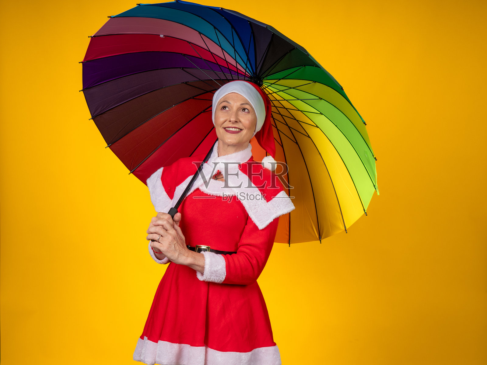 一位年长的女士在圣诞节打着彩虹伞庆祝照片摄影图片