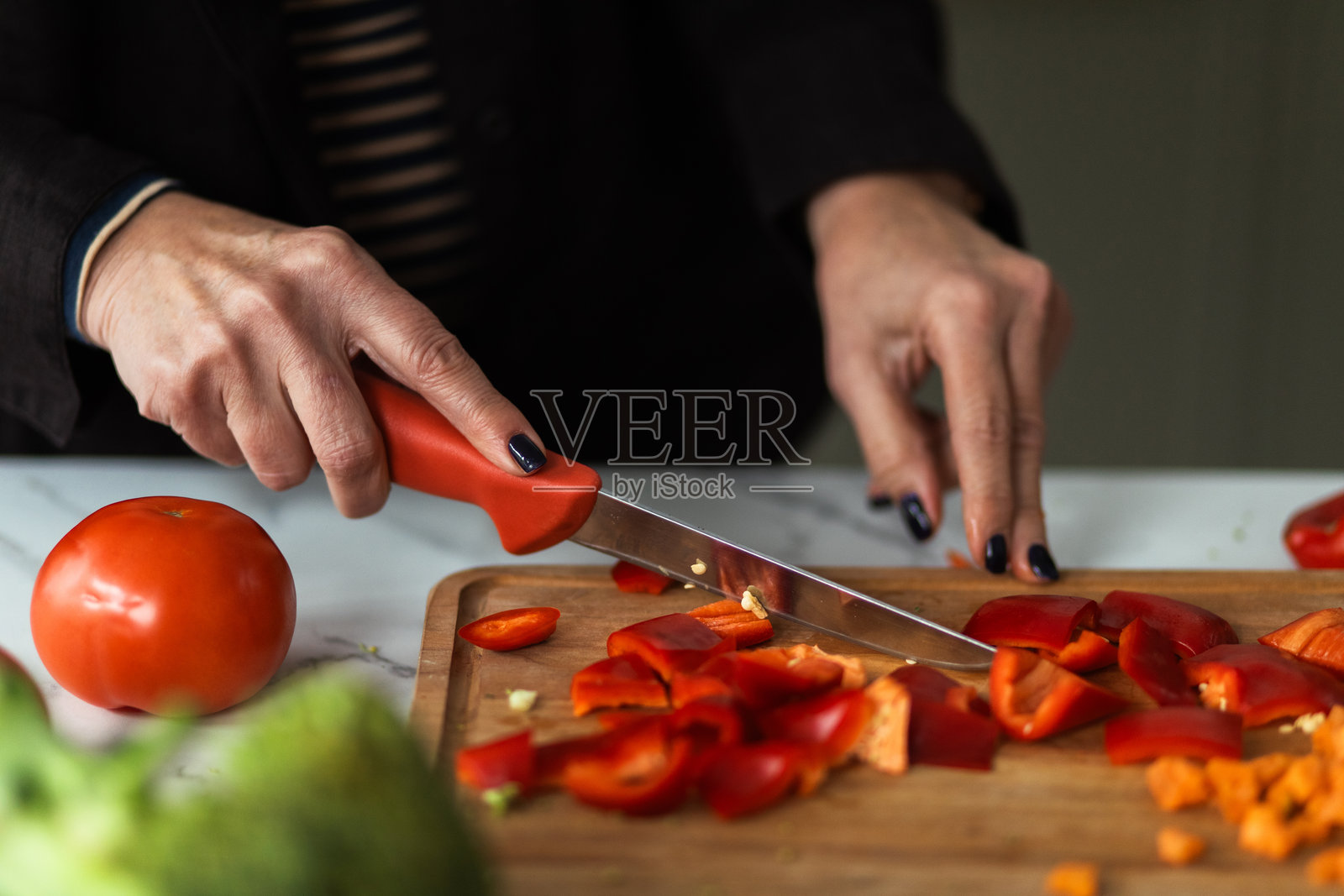 一位成年女性在砧板上切红甜椒的手照片摄影图片