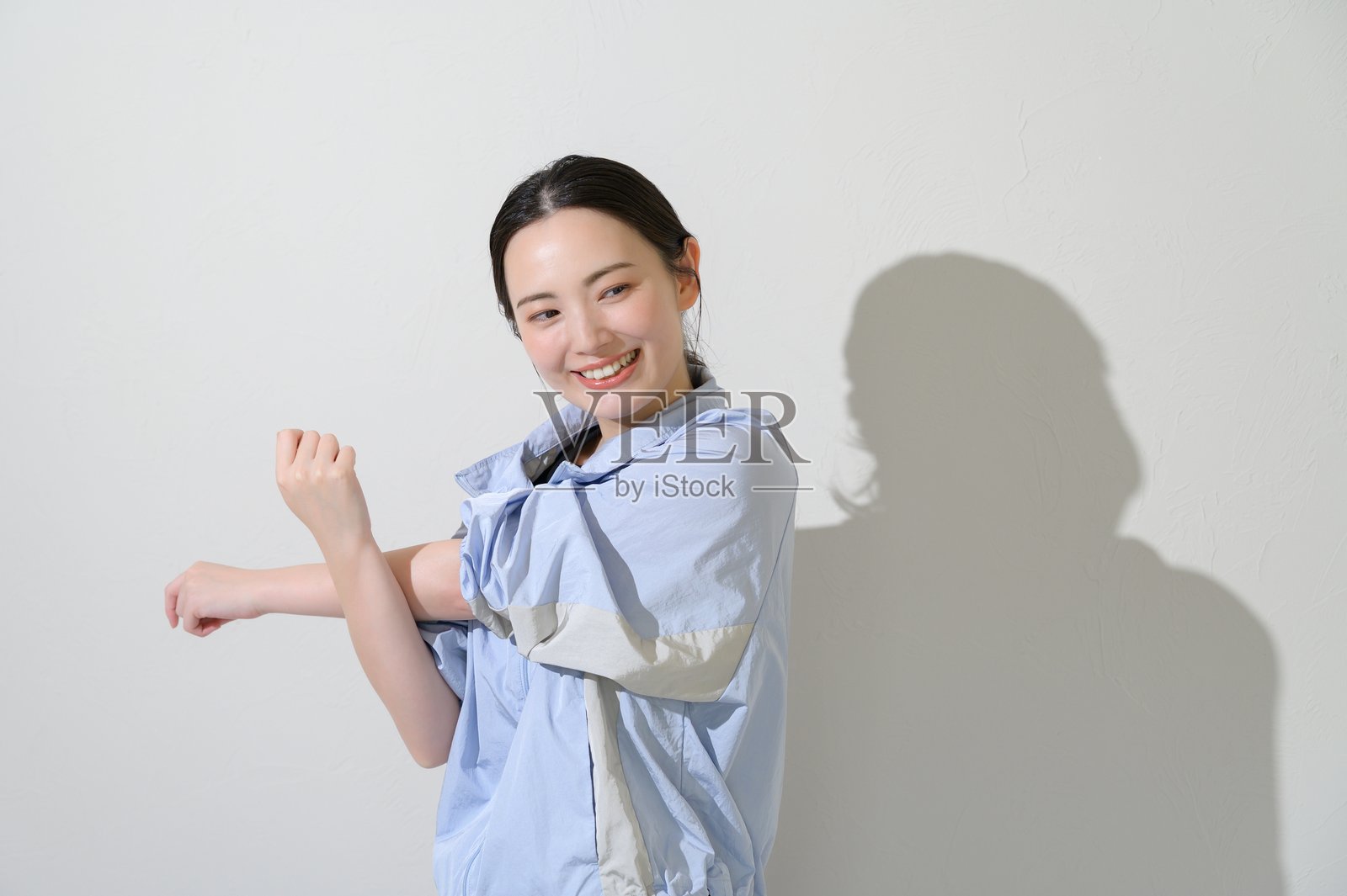 身着运动服的日本女性在白色背景上做伸展运动照片摄影图片