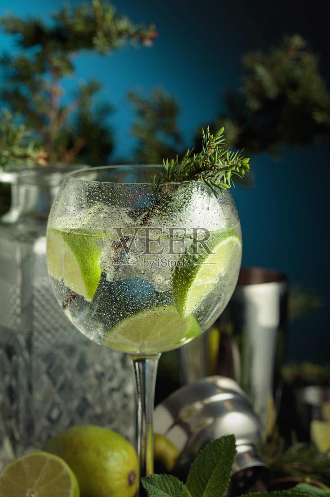 潮湿的玻璃杯中放有杜松子酒汤力鸡尾酒,配有冰块和青柠片。照片摄影图片