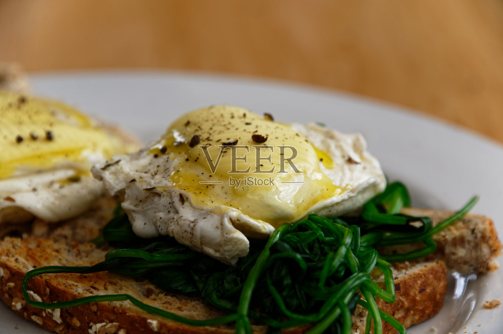 全麦吐司上的水波蛋,配有菠菜,顶部有融化的黄油。照片摄影图片