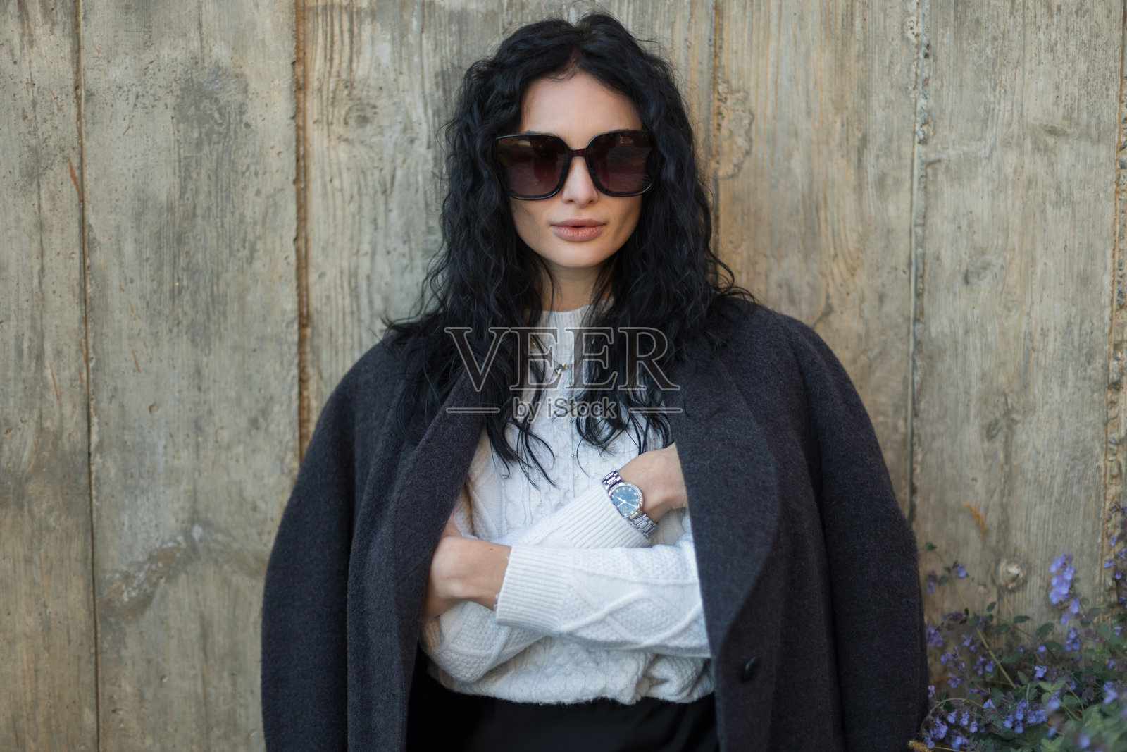 一位优雅的棕发模特身穿时尚的灰色外套和太阳镜,自信而别致。这是一幅展示秋季时尚潮流的户外生活方式肖像。照片摄影图片