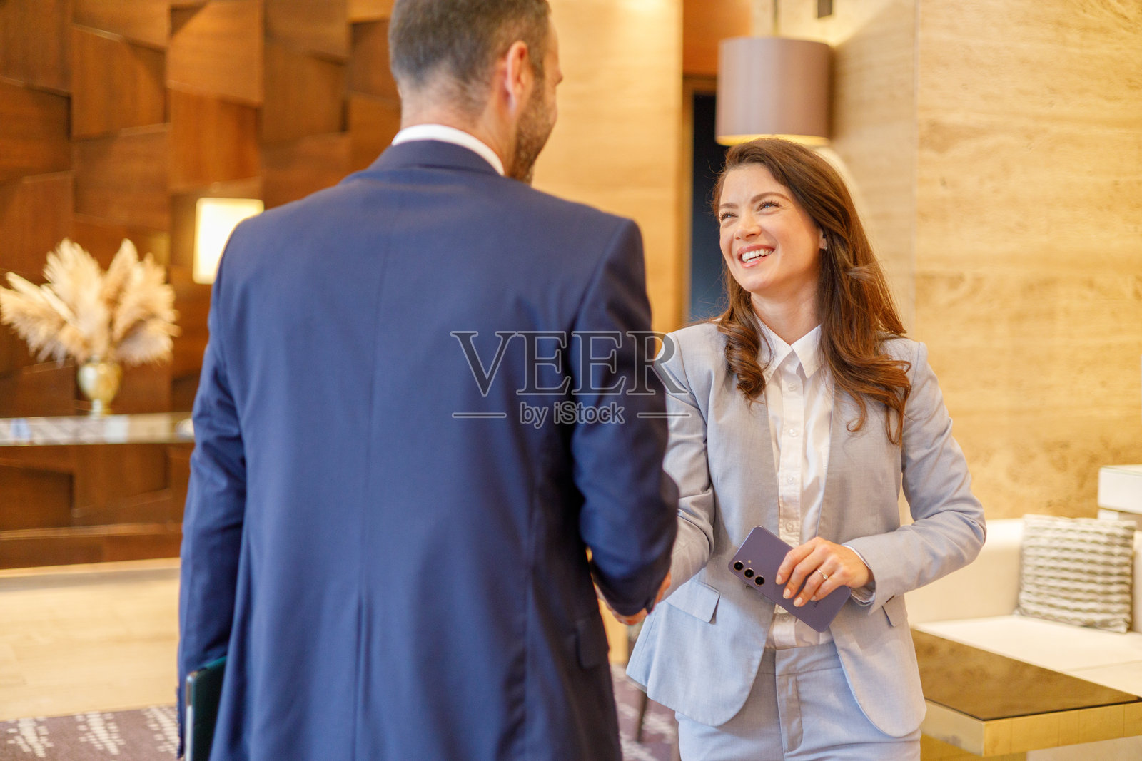 女商人与男商人握手,在公司大堂达成协议,面带微笑照片摄影图片