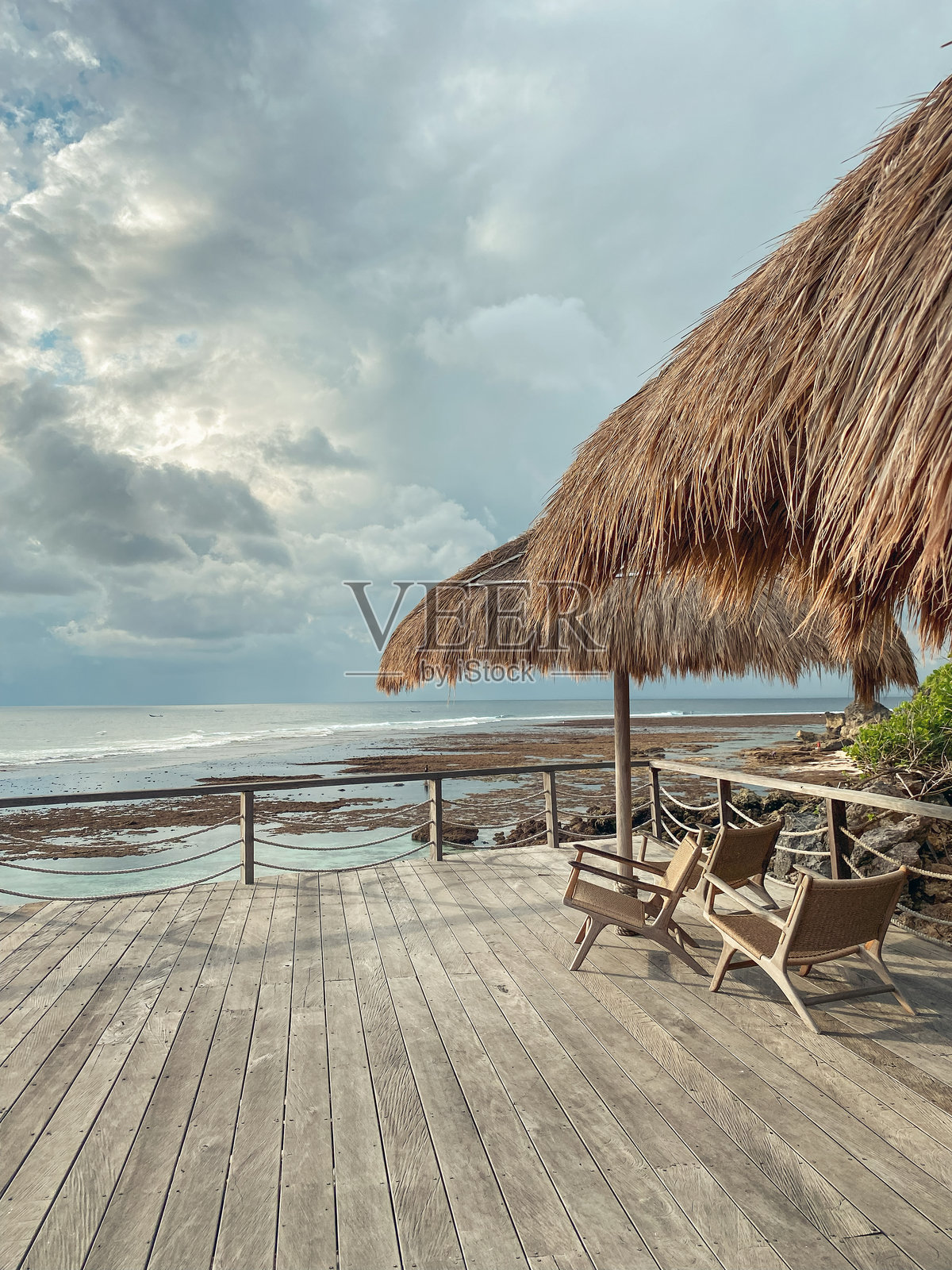 木制露台,带有茅草沙滩伞和日落景观照片摄影图片