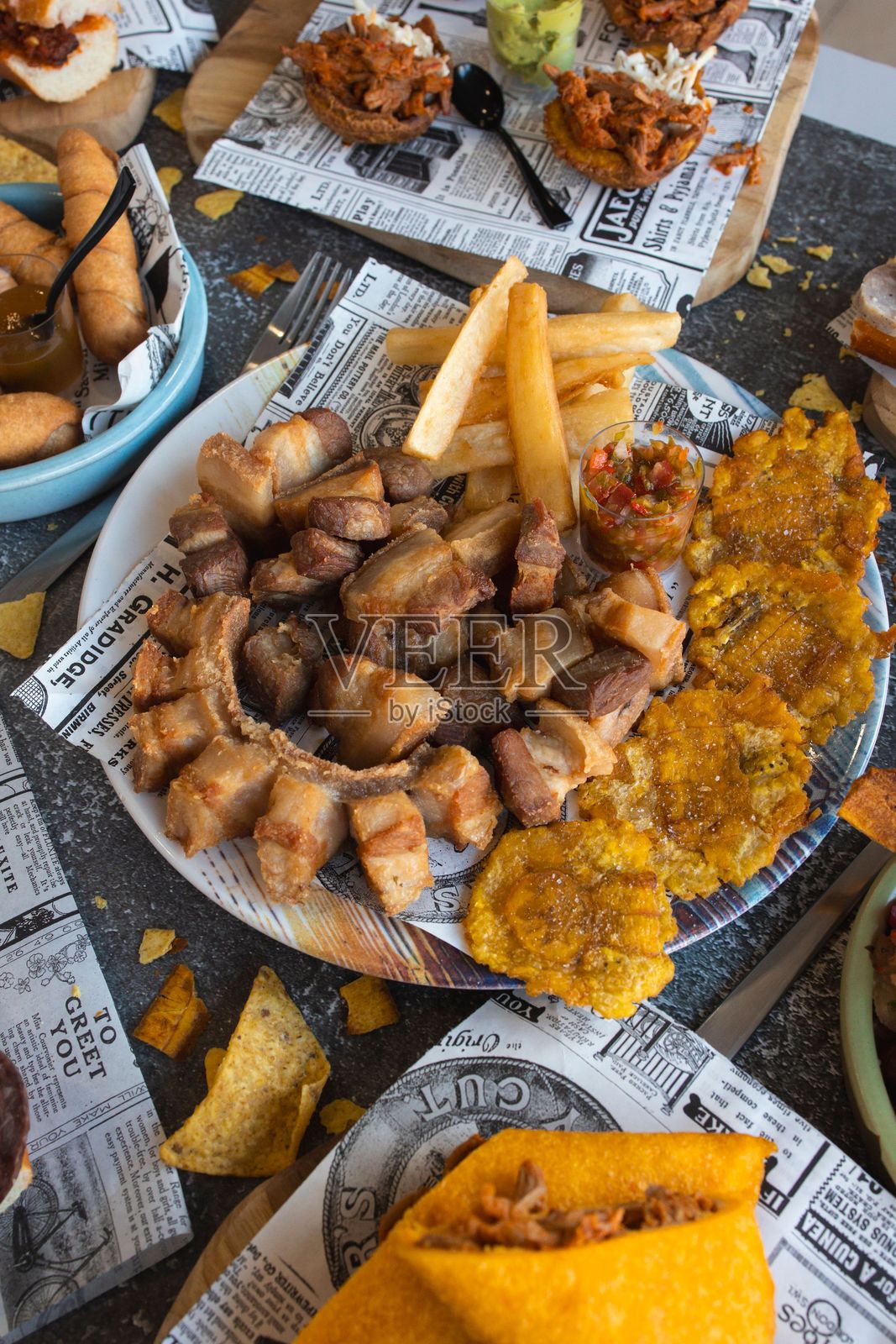 桌上摆放着色彩鲜艳的拉丁美洲美食,包括炸猪皮、炸大蕉片和木薯条。照片摄影图片