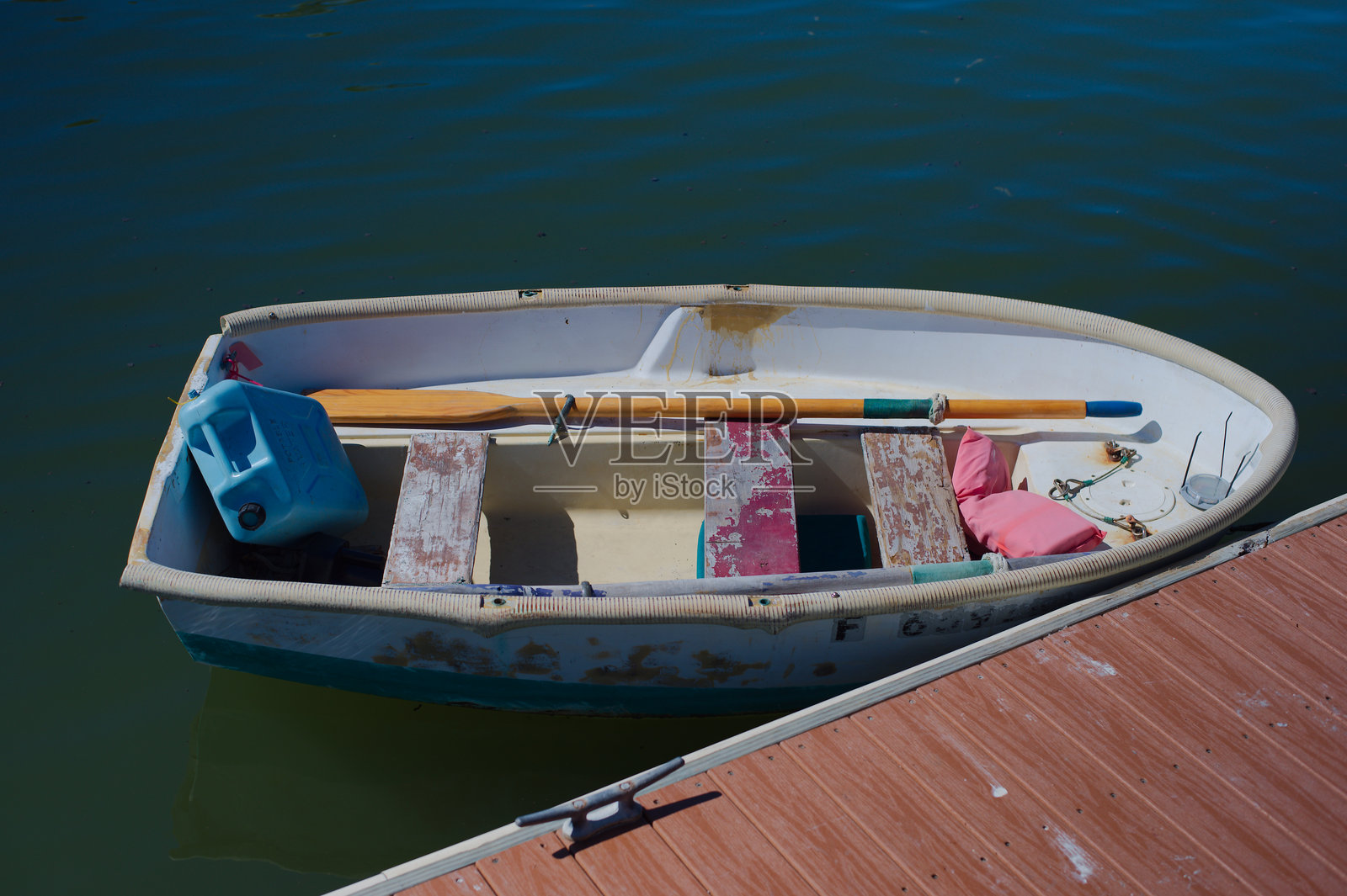 停靠在阳光码头的饱经风霜的划艇(配有船桨),宁静的海滨景象,位于佛罗里达州海湾港照片摄影图片
