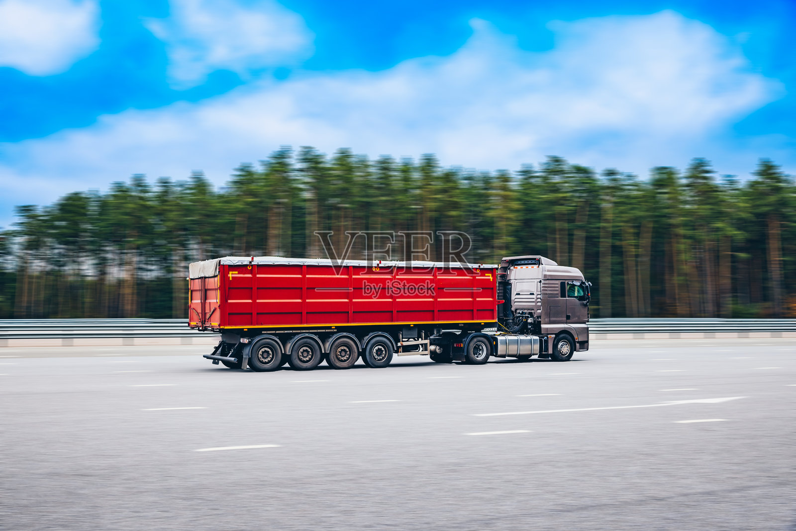 欧洲红色卡车在乡村风景的沥青路上飞驰。交通运输、配送和货物概念。照片摄影图片