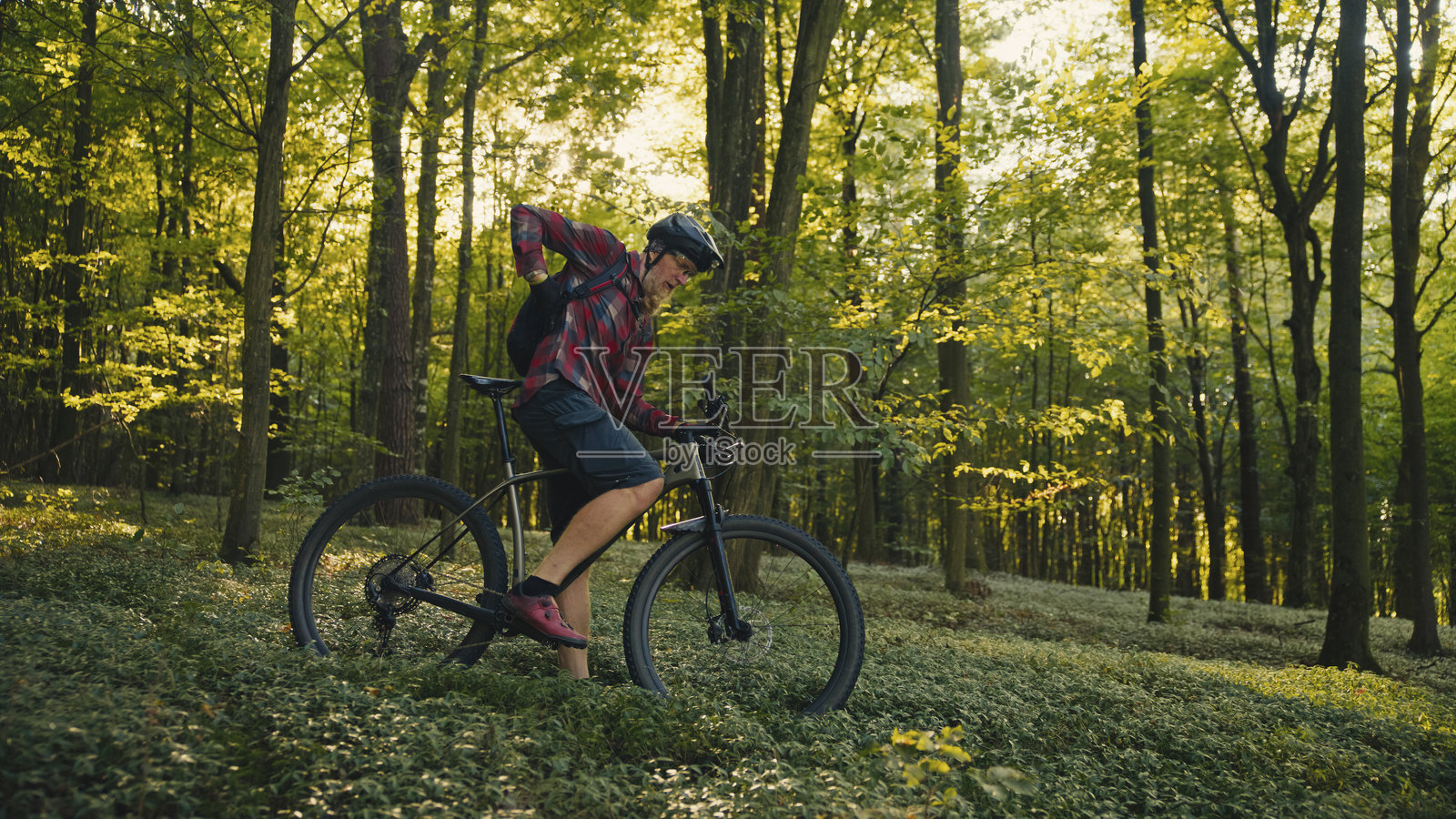 精力充沛的中年白种男性骑行者,在葱郁的阳光森林小径上骑行照片摄影图片
