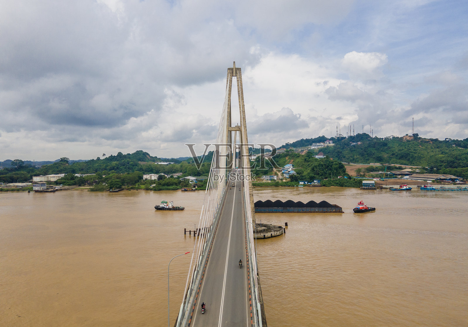从空中俯瞰,婆罗洲至关重要的交通动脉——三马林达的玛科塔二桥。车辆在桥上通行,煤炭驳船则在下方的马哈坎河上航行。照片摄影图片