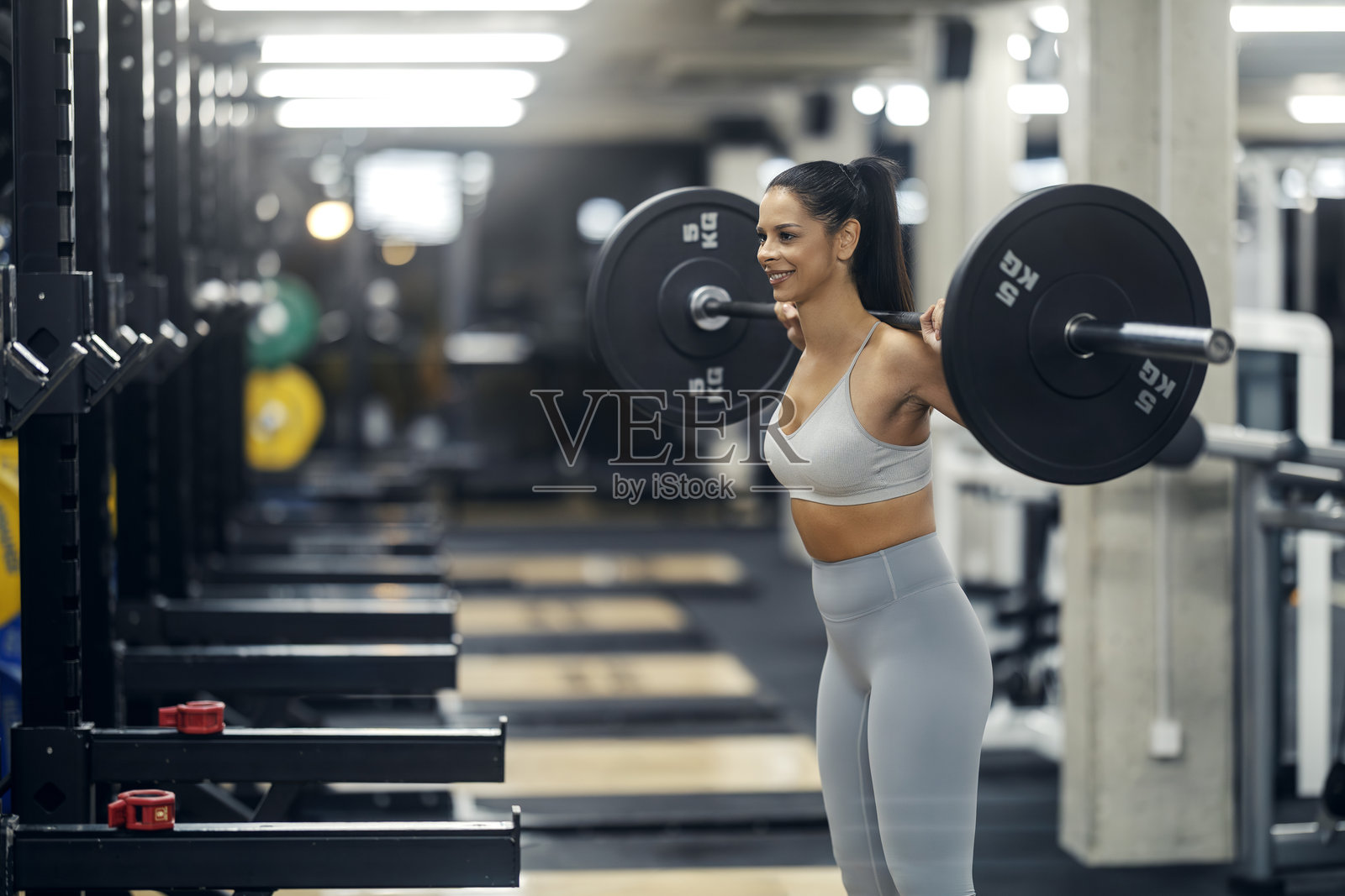 女性在健身房进行杠铃深蹲锻炼照片摄影图片