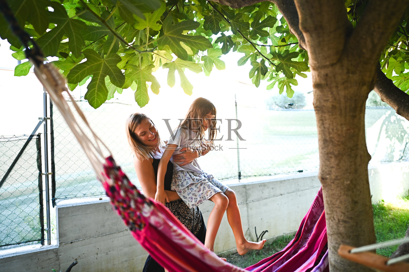 妈妈帮女儿爬进花园吊床照片摄影图片